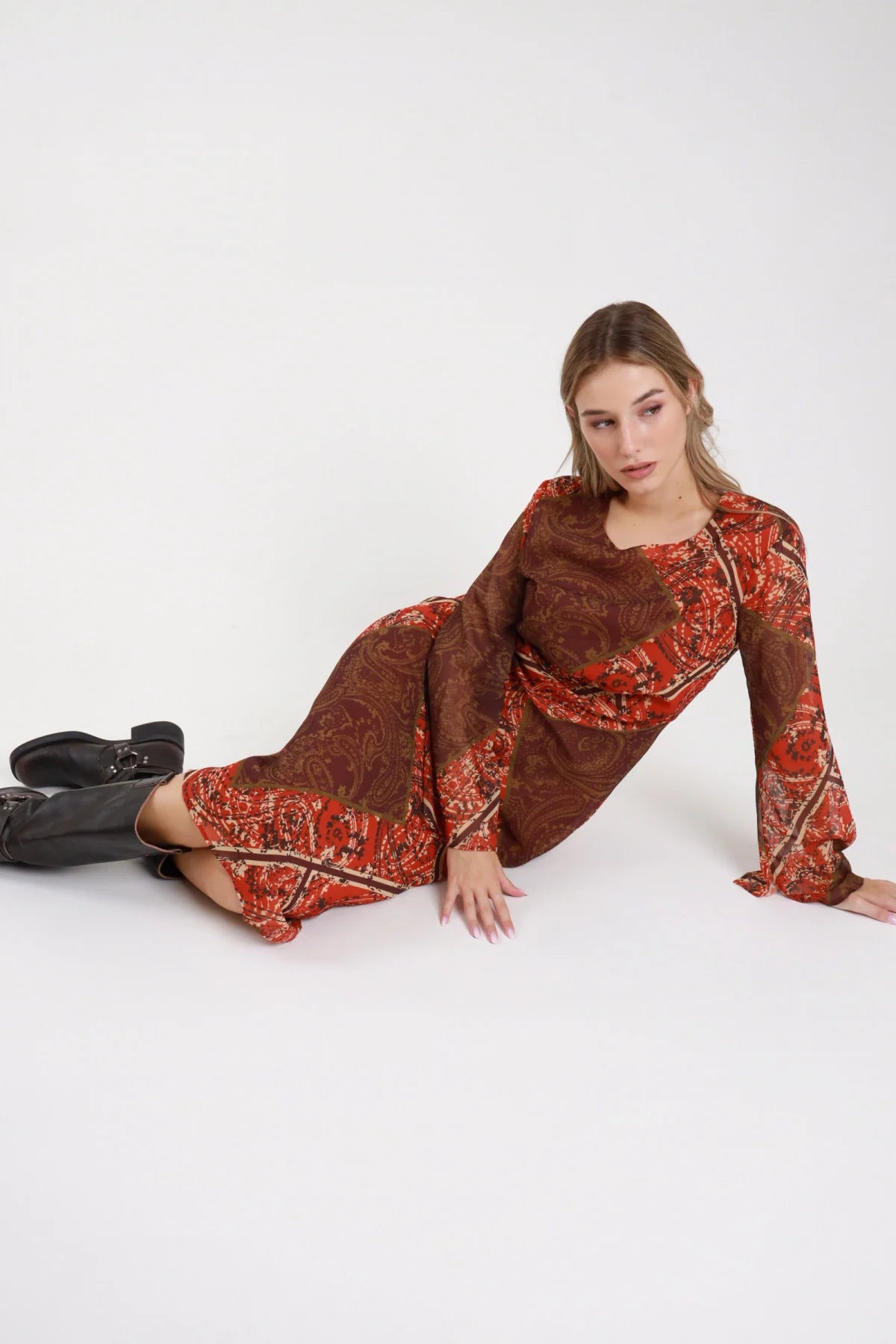 Dress paisley midi chiffon rosso borgogna cioccolato seduta sul pavimento intera manica campana flare gonna - modella seduta sul pavimento tre quarti sguardo frontale stivali neri capelli biondi ondulati raccolti
