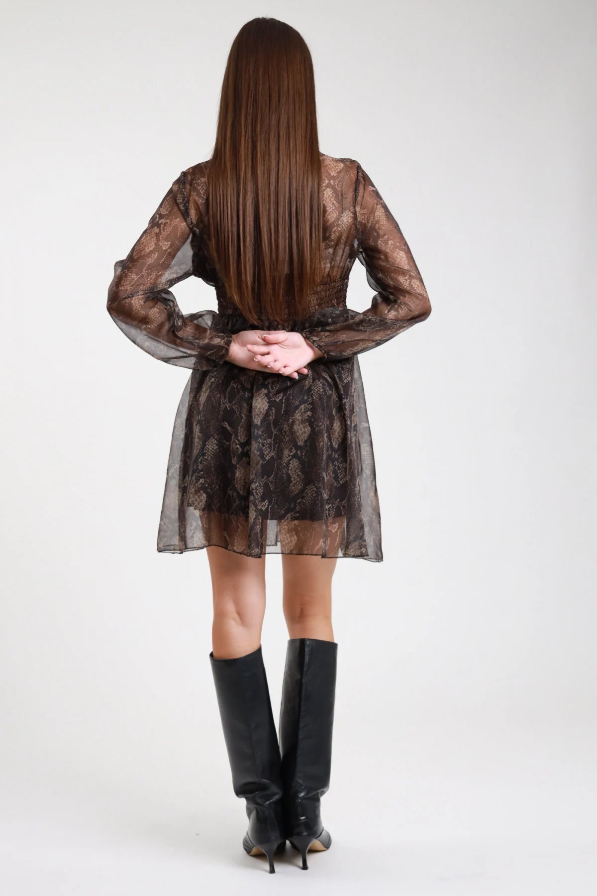 Abito corto animalier serpente pitone retro intera manica lunga voile polsino elastico gonna svasata - modella retro intera mani giunte retro sguardo posteriore stivali al ginocchio neri capelli castani lisci lunghi
