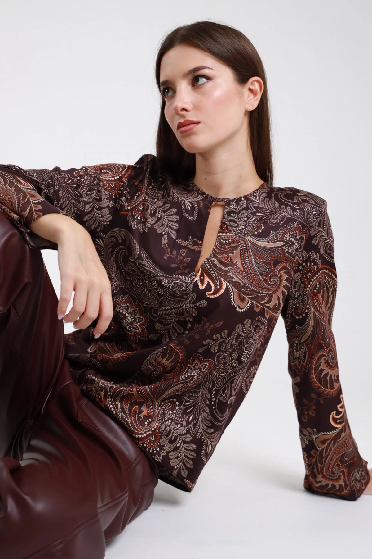 Blusa viscosa fantasia paisley bordeaux rame - modella seduta vista tre quarti con pantaloni bordeaux