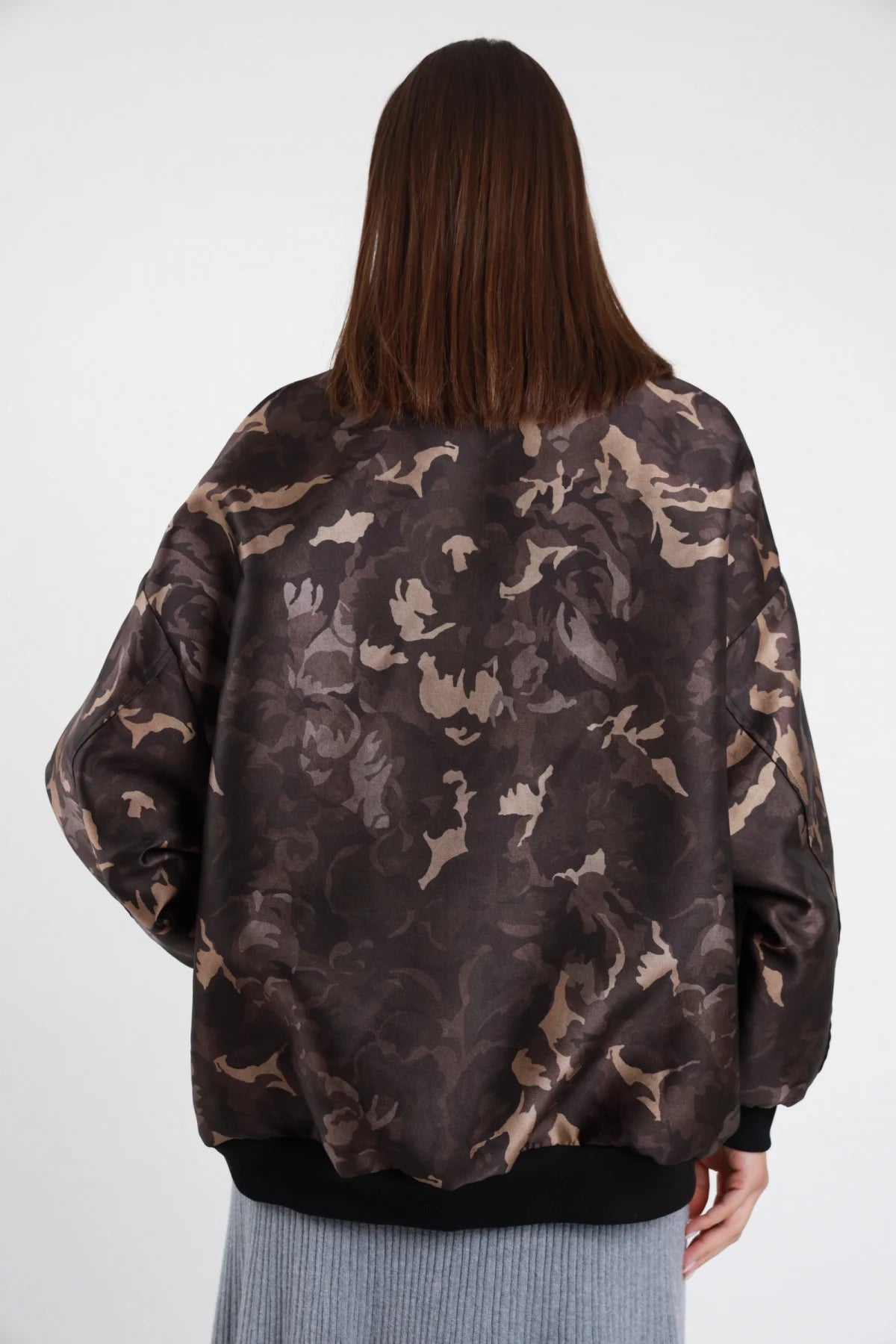Bomber Over Mimetico camouflage marrone verde khaki 100% poliestere retro liscio pattern camouflage macromotivo maniche oversize ampie bordo fondo costina nera posteriore intera - modella intera posteriore capelli castani lisci sfondo bianco gonna lunga coste azzurro melange