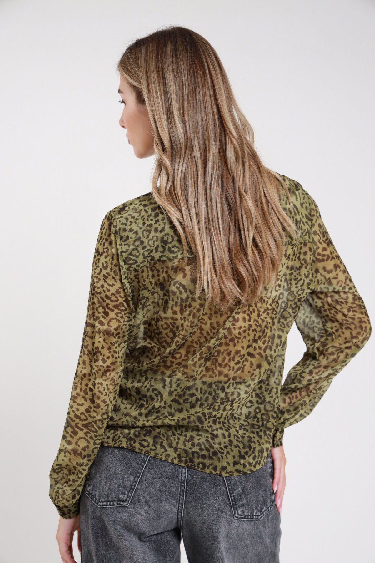 Camicia animalier chiffon semi-trasparente verde militare - modella vista posteriore busto dettaglio trasparenza tessuto capelli sciolti con jeans grigio