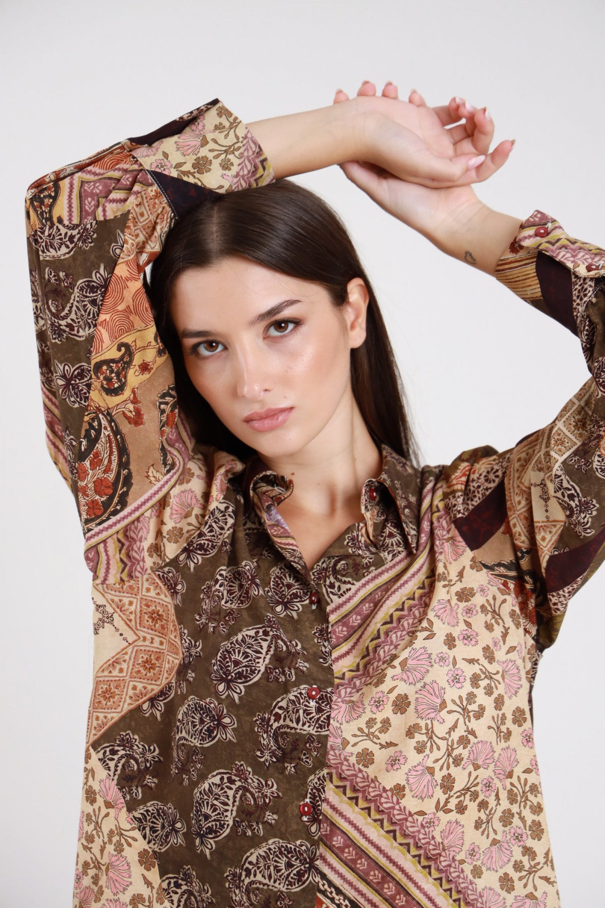 Camicia fantasia patchwork paisley baroque floral bordeaux prugna panna ecru rosa antico multicolor dettaglio frontale busto mani testa colletto classico punta ribaltabile bottoni gioiello bordeaux manica balloon bishop polsino maxi turn-up contrasto fantasia - modella frontale busto mani testa sguardo frontale intenso capelli castani lisci sfondo bianco
