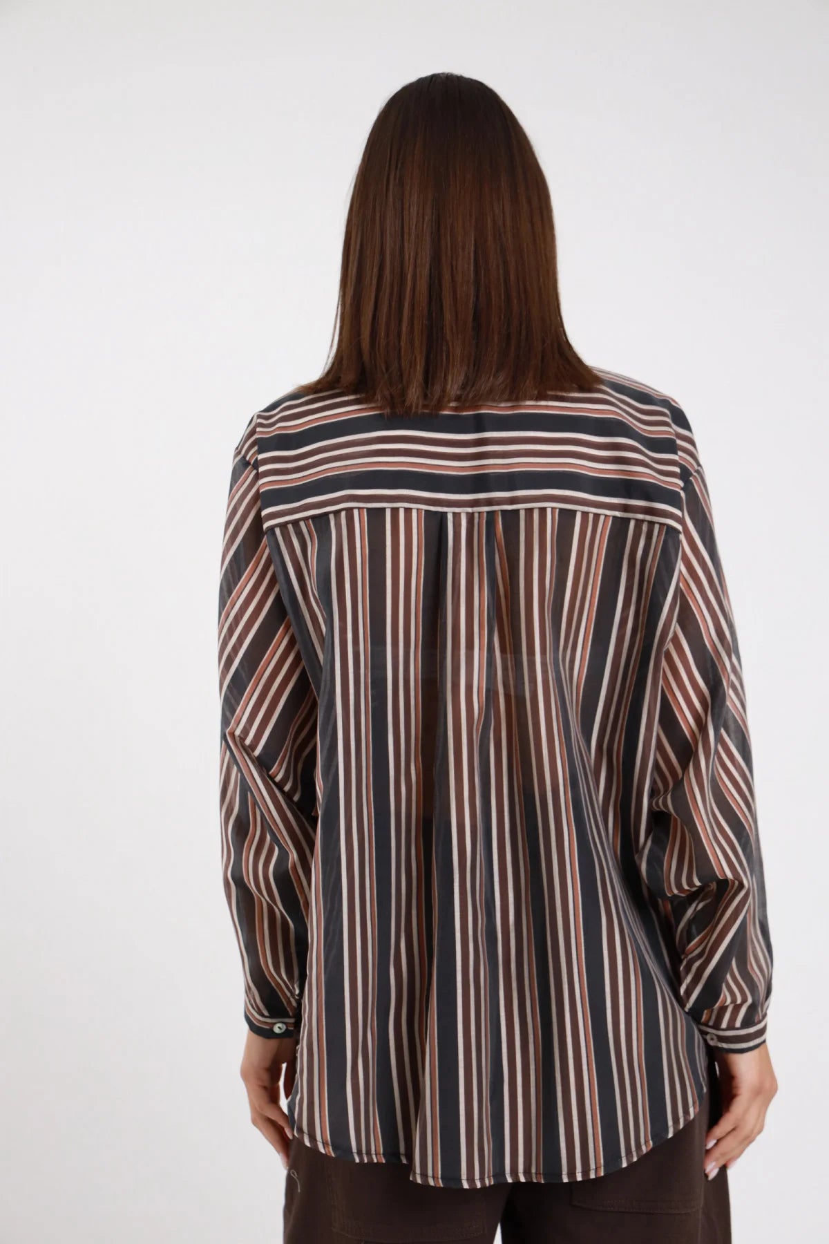 Camicia Righe verticali multicolore nero terracotta avorio azzurro oversize batwing orlo asimmetrico retro intera schiena silhouette fluida - modella retro intera sguardo abbasso capelli castani lisci sfondo bianco pantalone marrone scuro