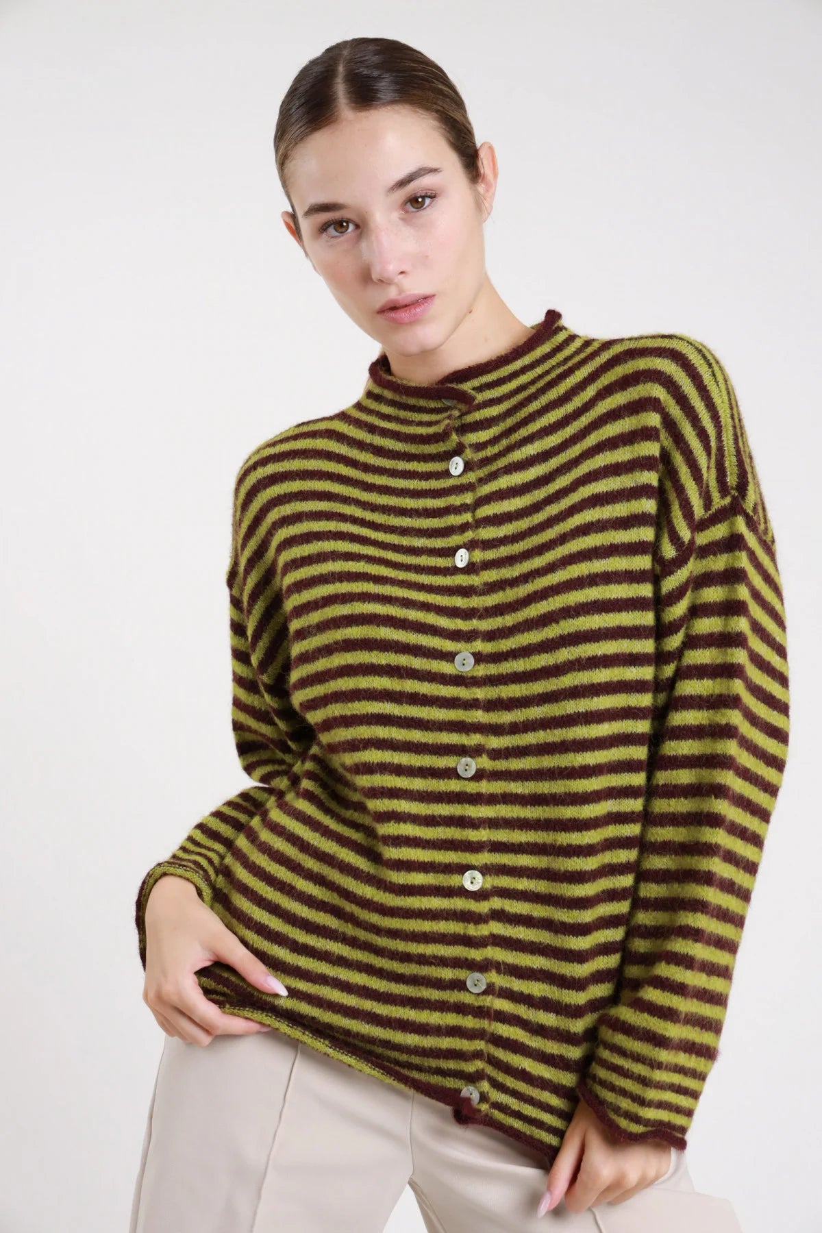 Cardigan righe lime moro verde oliva frontale busto mani tasche abbottonatura frontale bottoni perlati collo alto bordo moro dropped shoulder - modella frontale busto mani tasche sguardo frontale pantaloni beige capelli castani lisci raccolti