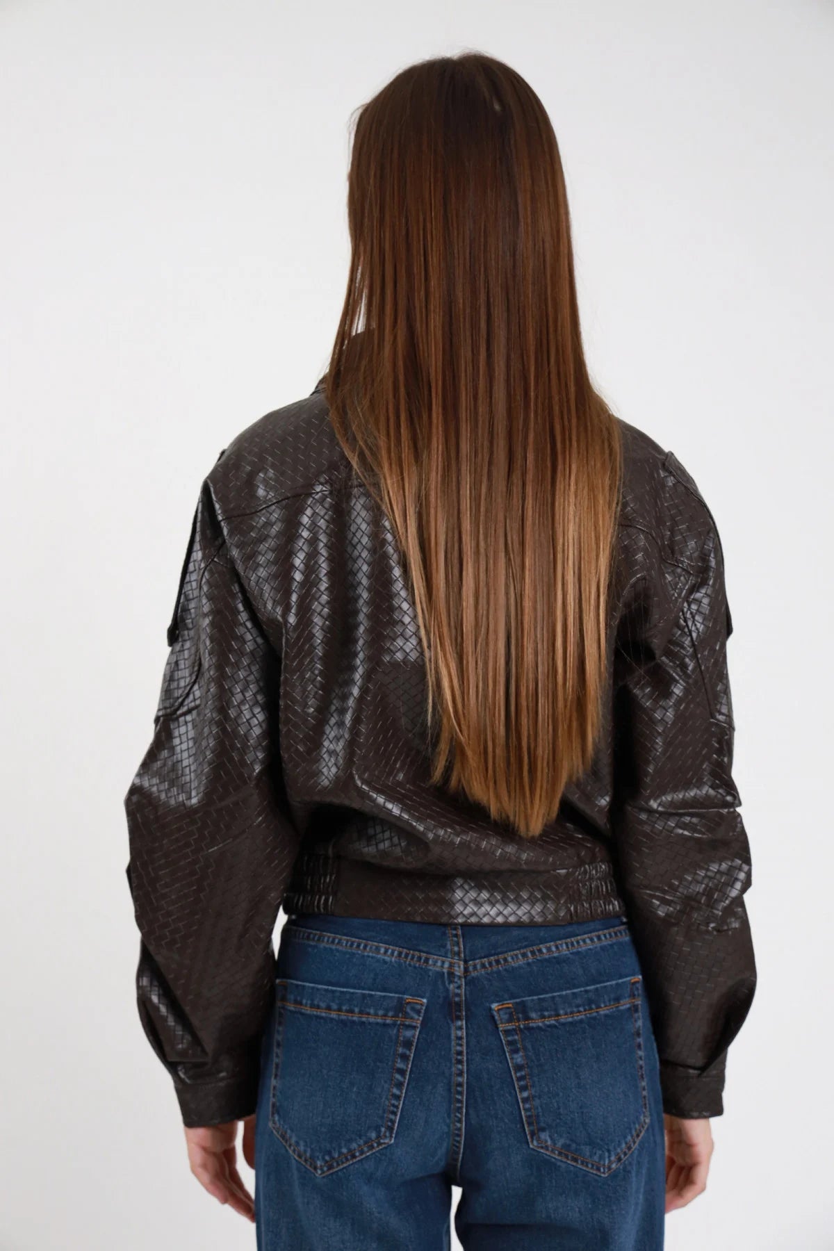 Chiodo ecopelle intrecciato rombi marrone scuro donna oversize fondo elasticizzato tasche maniche bottoni pressione argento - vista posteriore con jeans blu