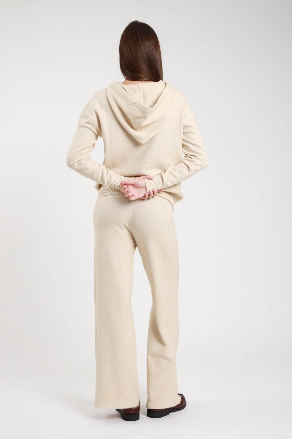 Completo maglia boucle bordeaux carminio hoodie pantalone wide leg seduta terra laterale cappuccio aperto cordoncino aglet manica dropped shoulder polsino corpo oversize pantalone gamba palazzo - modella seduta terra laterale mano cappuccio sguardo camera capelli neri lisci