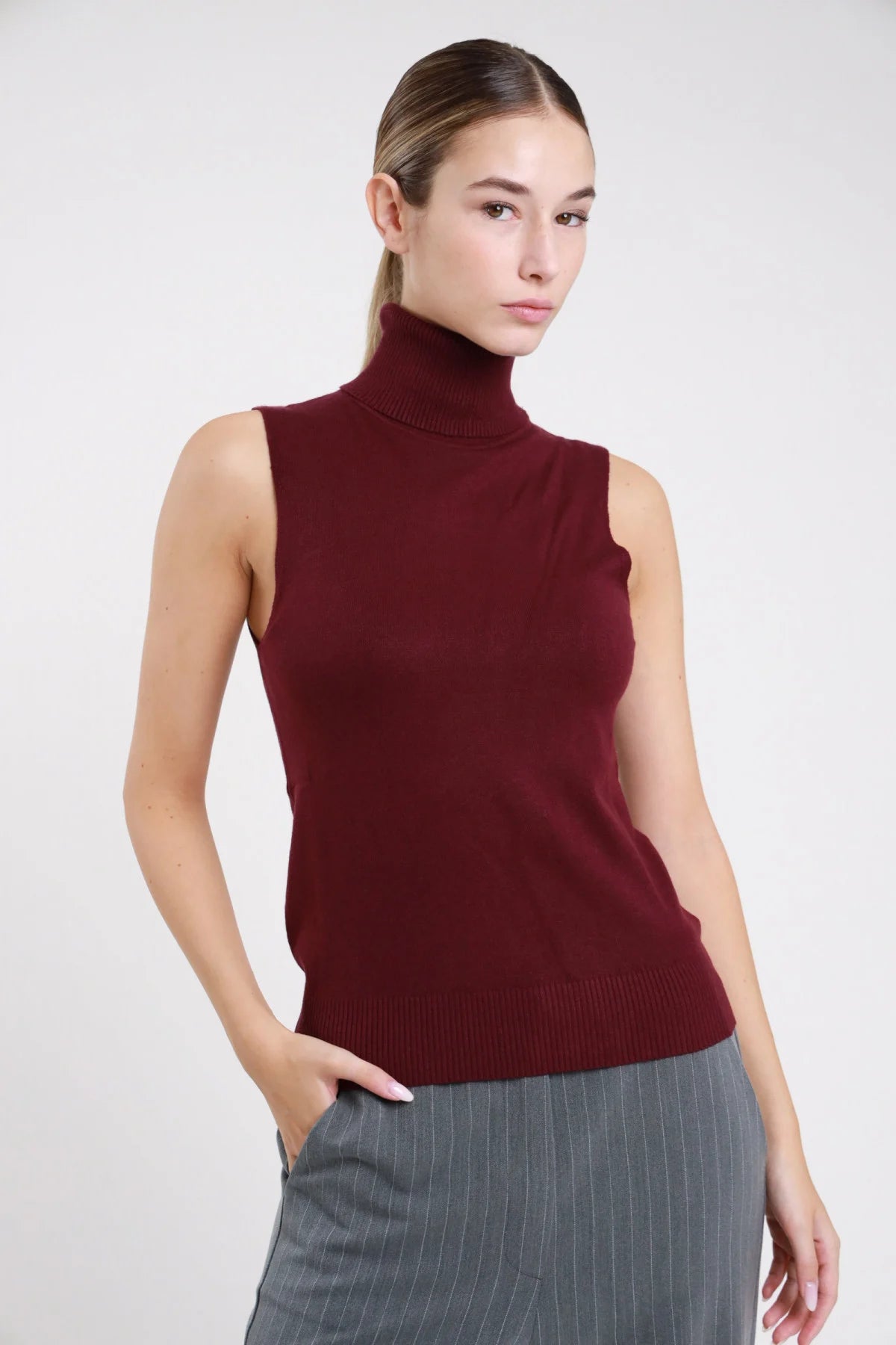 Dolcevita smanicato maglia bordeaux vinaccia slim fit - modella busto frontale mano in tasca con pantaloni gessato grigio