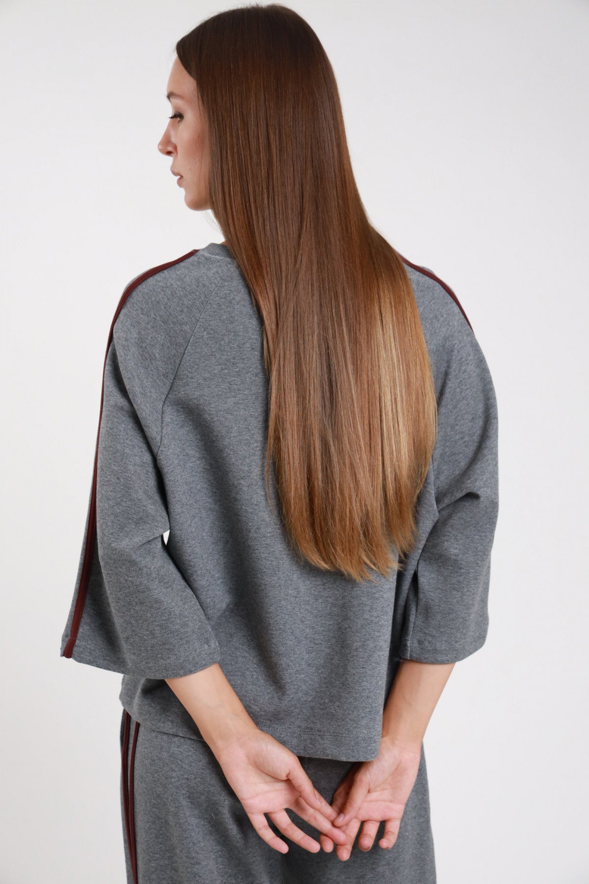 Felpa bande grigio melange retro intera bande borgogna doppie spalla manica 3/4 corpo oversize orlo dritto vita - modella retro intera mani intrecciate dietro sguardo basso laterale pantaloni grigio coordinato capelli castani lunghi lisci