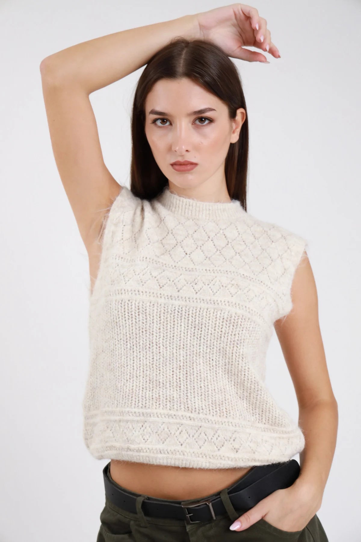 Gilet maglia eyelash bouclé traforato rombi senza maniche girocollo crop avorio ecru beige chiaro frontale tre quarti braccio alzato pantaloni verde militare - modella frontale tre quarti braccio alzato sguardo frontale capelli castani scuri lisci sfondo bianco pantaloni verde militare cintura nera