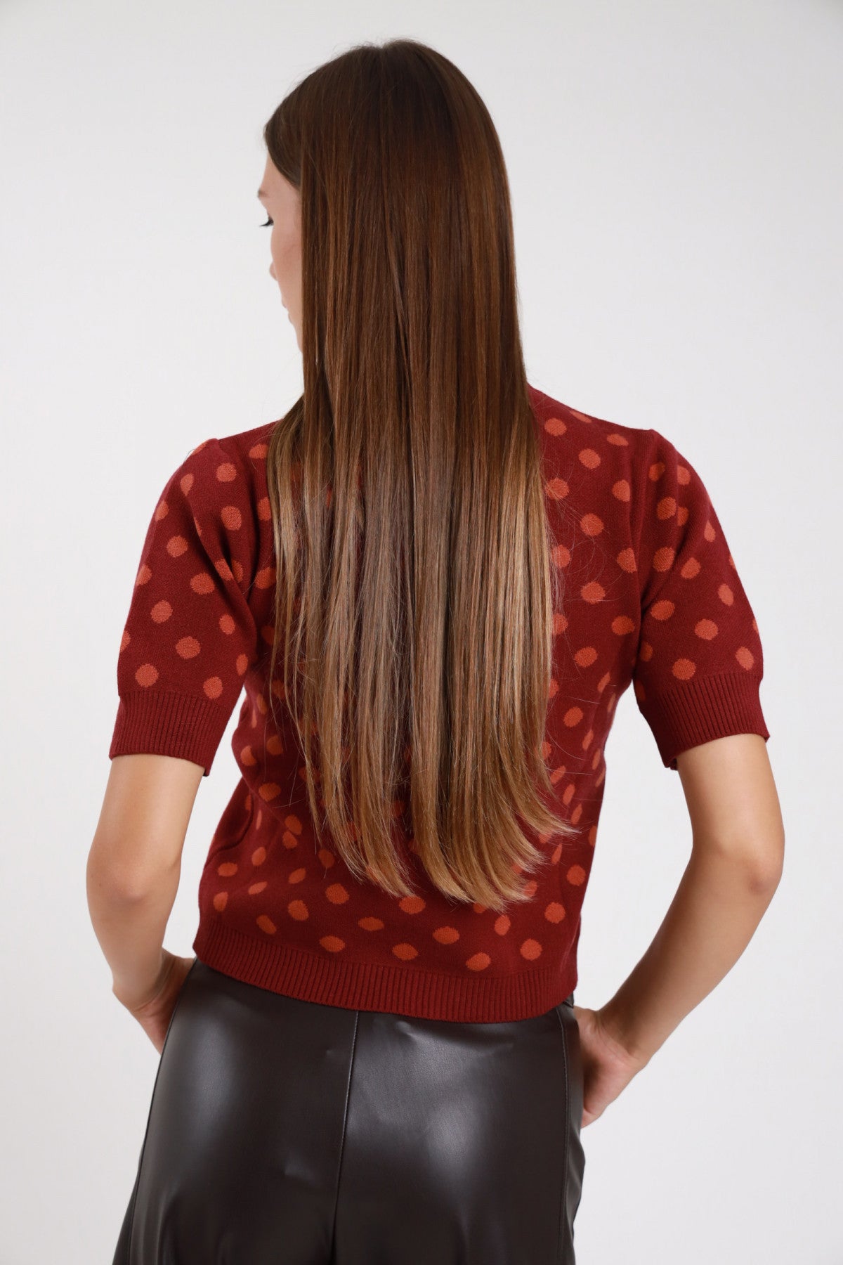 Pullover pois maxi jacquard borgogna corallo retro intera manica puff costina polsino orlo costina - modella retro intera mani fianchi sguardo posteriore pantaloni ecopelle nero capelli castani lunghi lisci