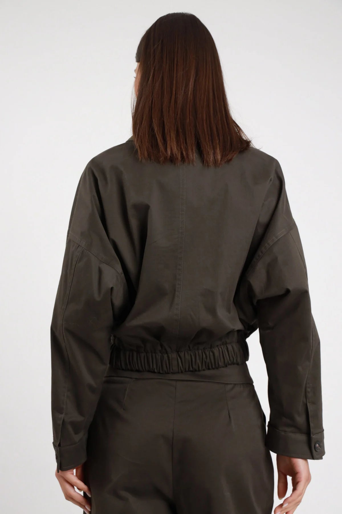 Bomber tasconi Susy Mix Pre-Fall verde militare elastico smock fondo arricciato ben visibile manica batwing oversize retro liscio posteriore busto - modella posteriore busto capelli scuri lisci sfondo bianco elastico smock fondo dettaglio pantalone piega verde militare coordinato abbinato