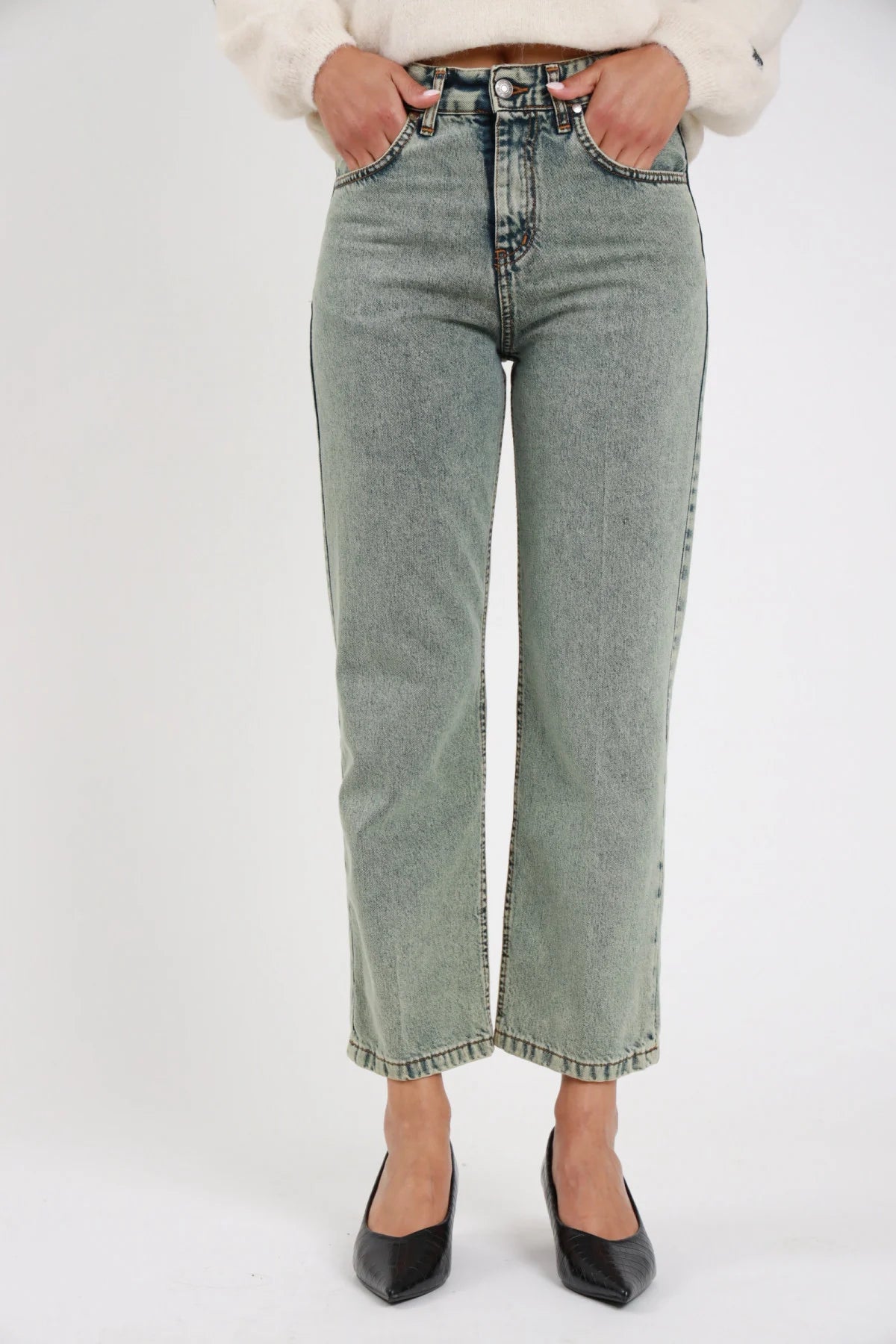 Jeans Manu straight leg verde sage acqua stonewashed rhinestone vita alta 5 tasche orlo grezzo close-up vita gamba frontale dettaglio tasche bottone zip - modella close-up vita gamba frontale mani tasche sguardo non visibile sfondo bianco décolleté neri kitten heel