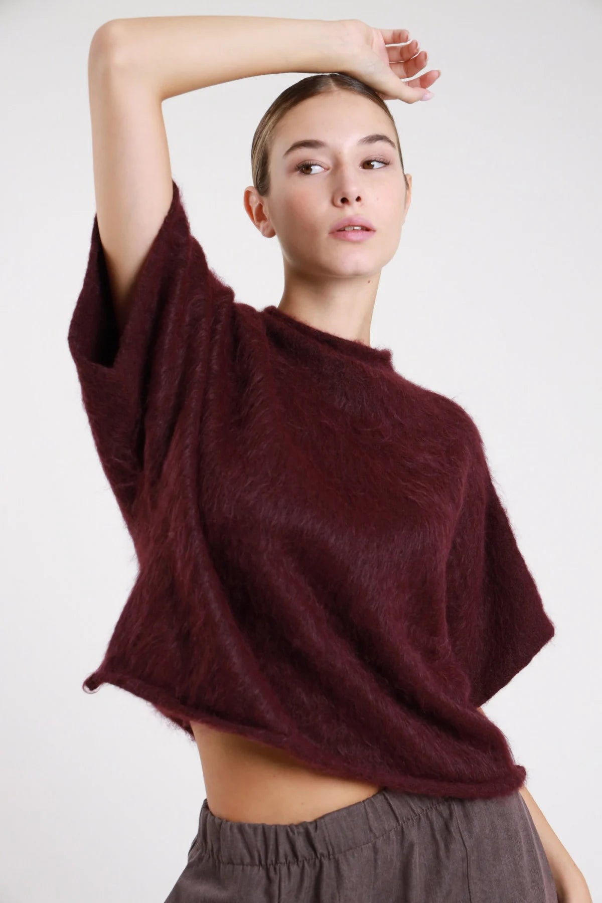 Pullover maniche corte dettaglio texture maglia spazzolata effetto mohair orlo sfrangiato grezzo - modella busto ravvicinato sguardo basso capelli castani raccolti