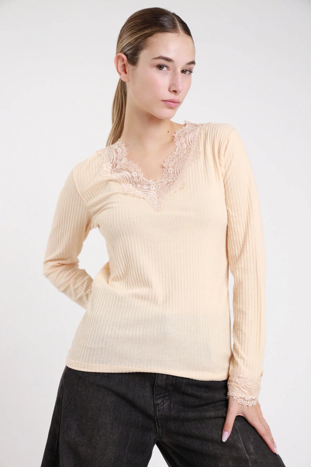 Maglia costina pizzo panna crema scollo V - modella busto tre quarti mano in tasca jeans neri sguardo laterale capelli raccolti