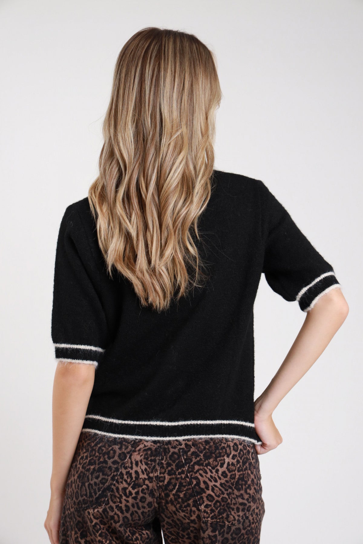 Polo maglia boucle cioccolato tabacco bordino eyelash rosa cipria frontale busto mano collo colletto polo punta bottoni madreperla bordino wavy ondulato manica corta dropped shoulder - modella frontale busto mano collo sguardo laterale basso jeans neri capelli castani raccolti