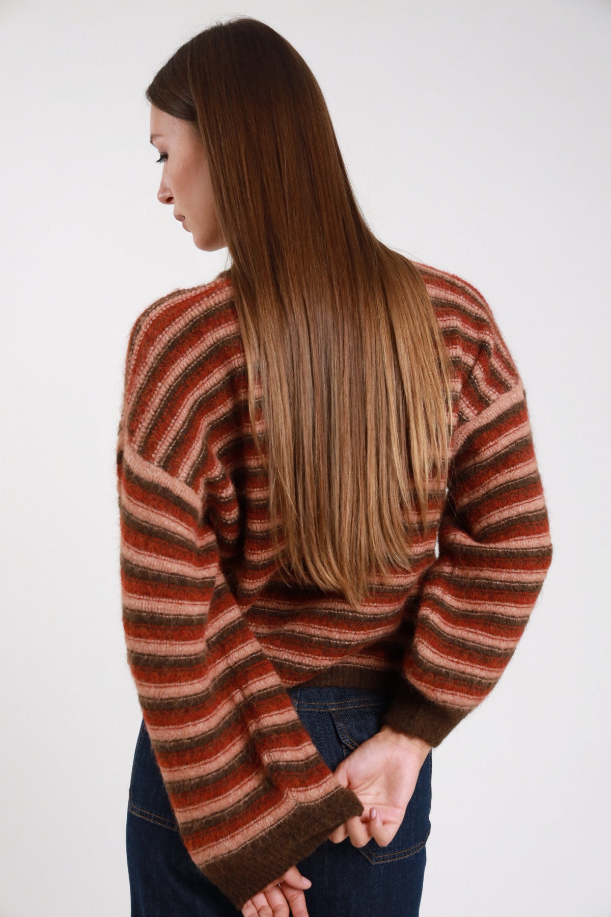 Maglione righe multicolor wave ruggine cotto cioccolato retro intera manica balloon polsino costina corpo boxy - modella retro intera mani dietro sguardo basso laterale jeans indaco stivali marroni capelli castani lisci lunghi