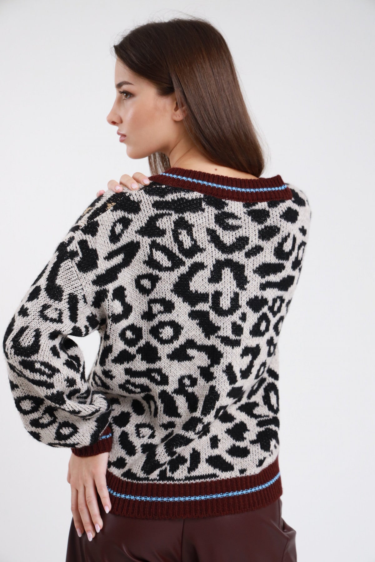 Pullover scollo V animalier leopardata panna avorio cognac nero jacquard frontale seduta mano vita scollo V bordino bicolor bordeaux azzurro corpo oversize relaxed orlo coste bicolor fianchi - modella frontale seduta mano vita sguardo camera jeans bordeaux capelli castani lisci