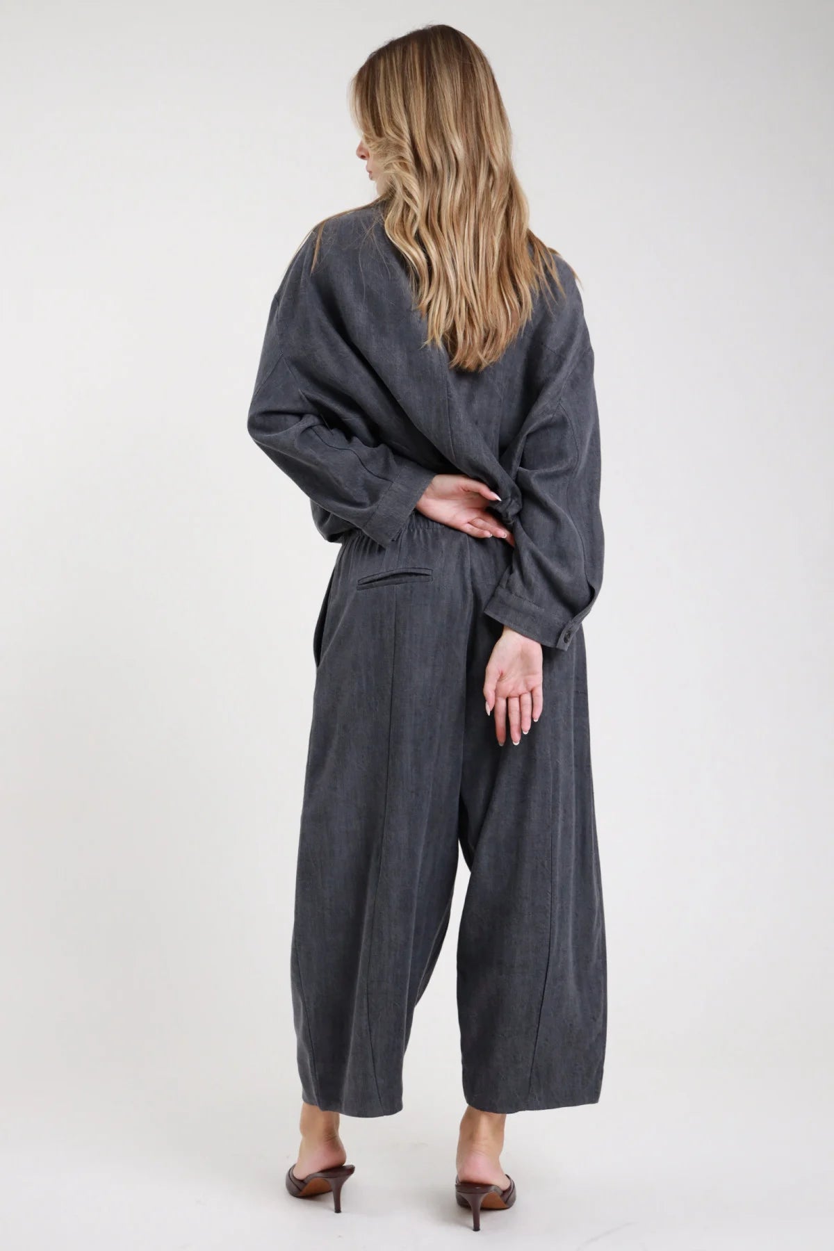 Pantalone gamba larga antracite grigio scuro lino 7/8 retro - modella retro intera mani intrecciate con bomber abbinato antracite mules bordeaux capelli biondi mossi