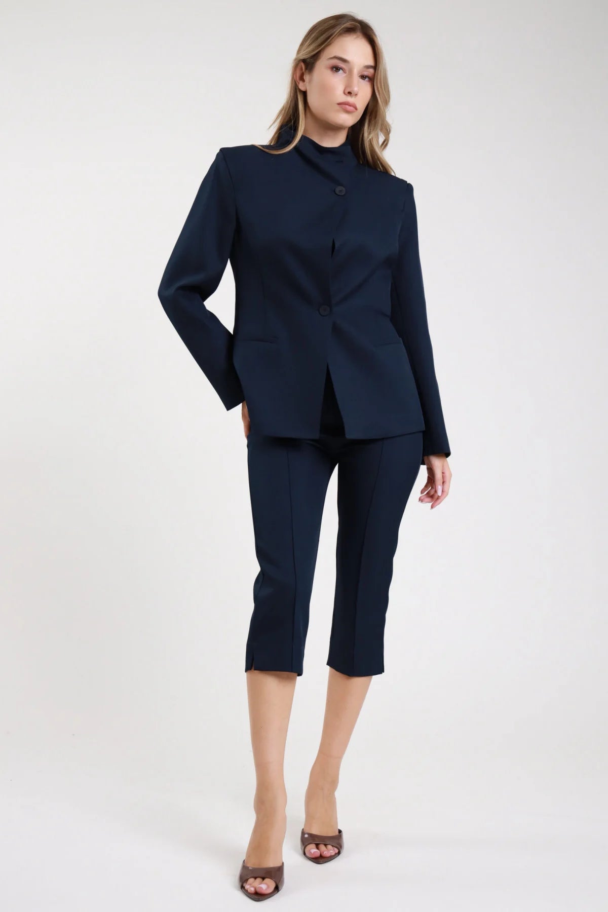 Pantaloni capri pinocchietto navy blu scuro sigaretta piega frontale spacco - modella frontale intera mano in tasca sguardo frontale sandali marroni capelli biondi mossi