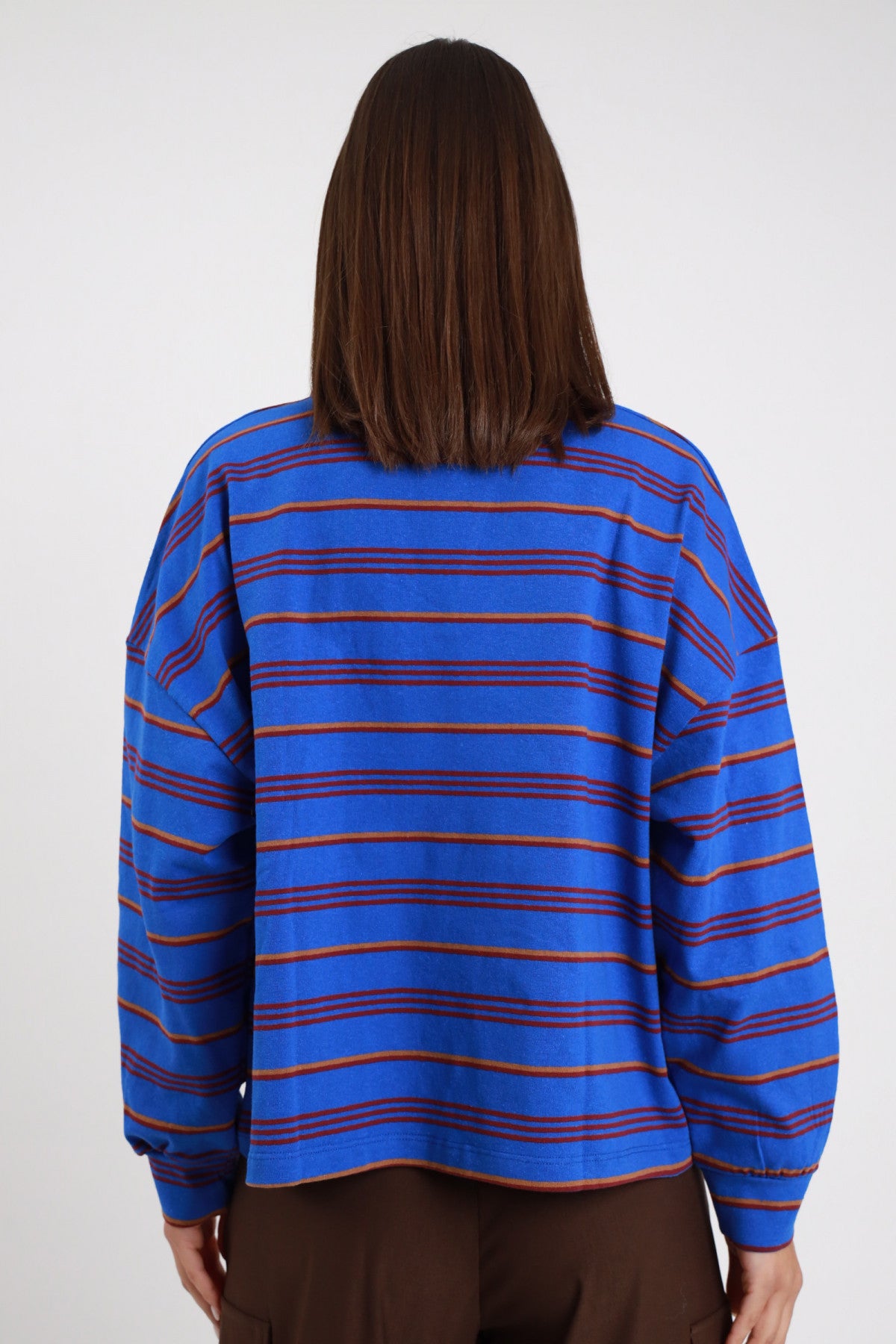 Polo Rugby Oversize Righe Multicolor Patch Varsity blu cobalto elettrico rosso arancio 77% cotone silhouette oversize boxy crop posteriore retro liscio righe manica drop polsino costina - modella intera posteriore posa statica capelli castani lisci sfondo bianco pantaloni marrone cioccolato
