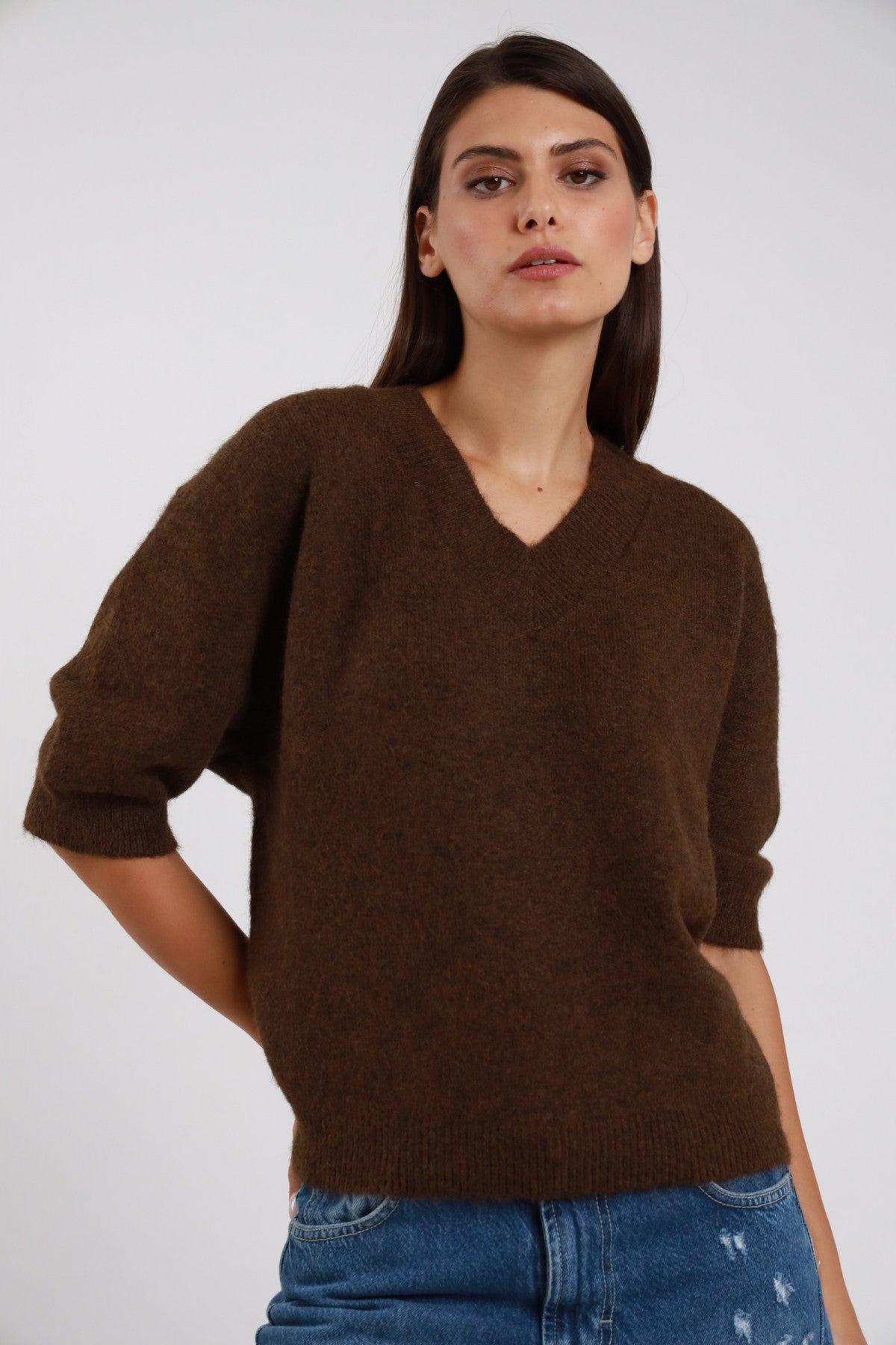 Pullover Scollo V marrone cioccolato moka maglia ultra morbida scollo V ampio manica 3/4 balloon risvolto orlo coste oversize boxy busto frontale 3/4 mano fianco sguardo frontale - modella busto frontale 3/4 mano fianco sguardo frontale capelli castani sfondo bianco jeans chiari