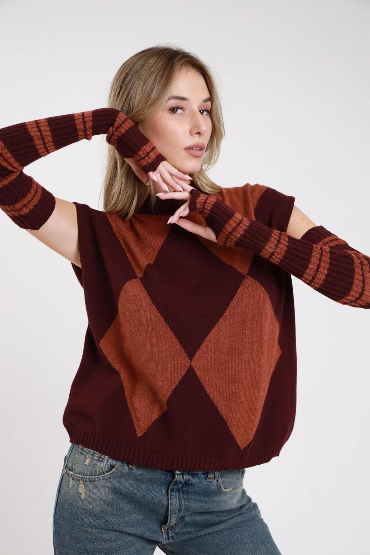 Pullover smanicato manicotti argyle cioccolato bordeaux retro intera cut-out spalla manicotti righe - modella retro intera mani dietro sguardo posteriore pantaloni ecopelle neri capelli castani lisci lunghi