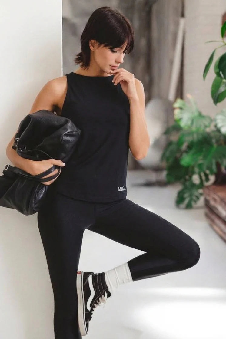 Canotta mika nuda nera spalle nude vista frontale con leggings neri e sneakers Vans