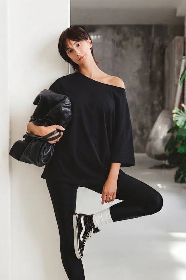 Maglia mika scema nera off-shoulder oversize vista frontale tre quarti con leggings neri e Vans