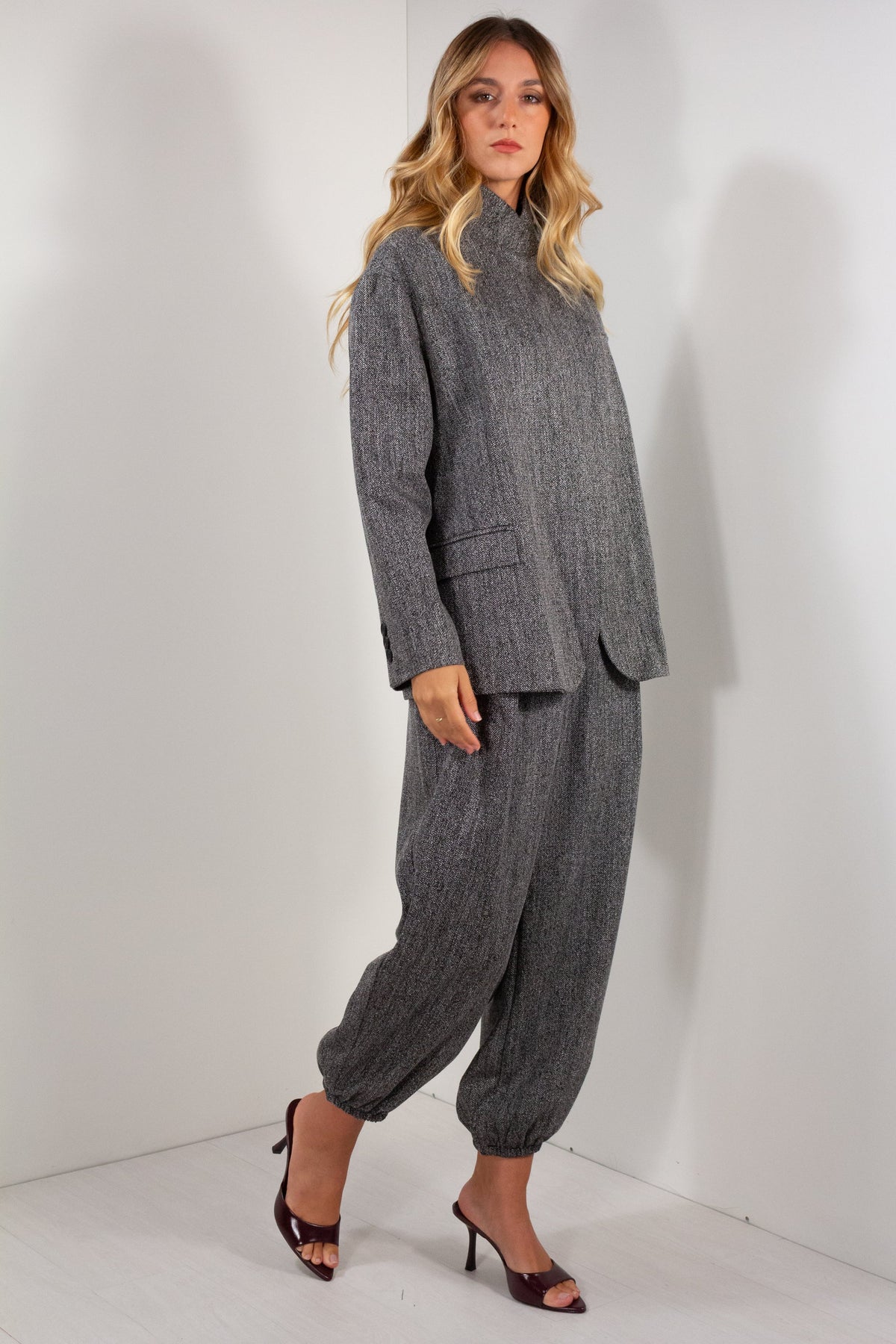 Completo giacca pantalone ovetto spigato grigio antracite vista laterale intera con maglia bordeaux e décolleté bordeaux