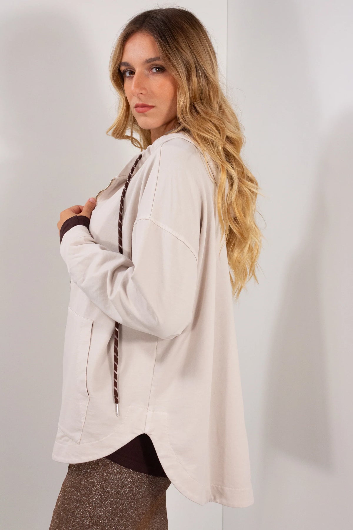 Felpa zip mika beige sabbia vista laterale con cappuccio e polsini marroni su gonna lurex dorata