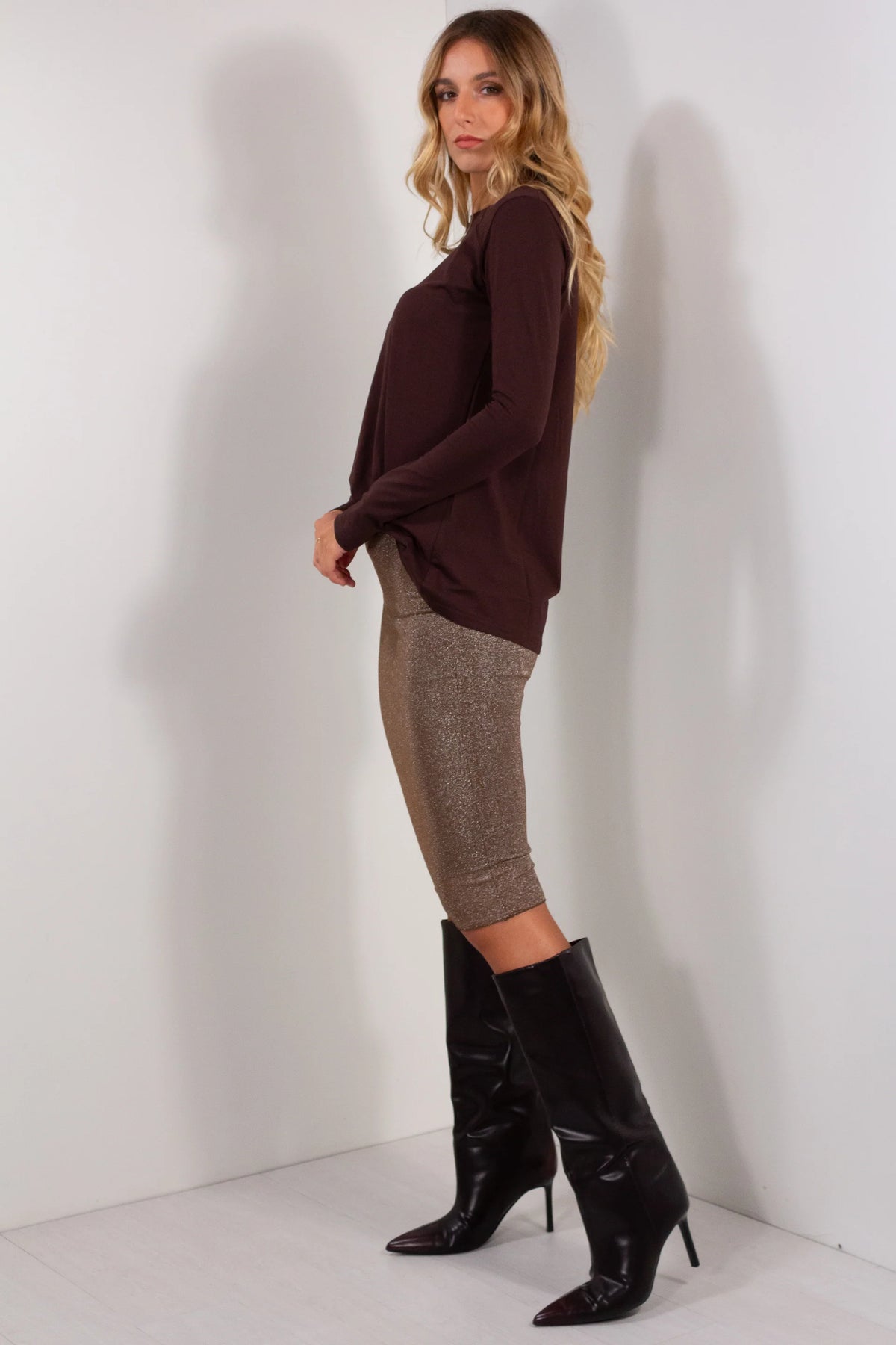 Gonna tubino lurex dorato bronzo vista laterale con maglione marrone cioccolato e stivali neri con tacco