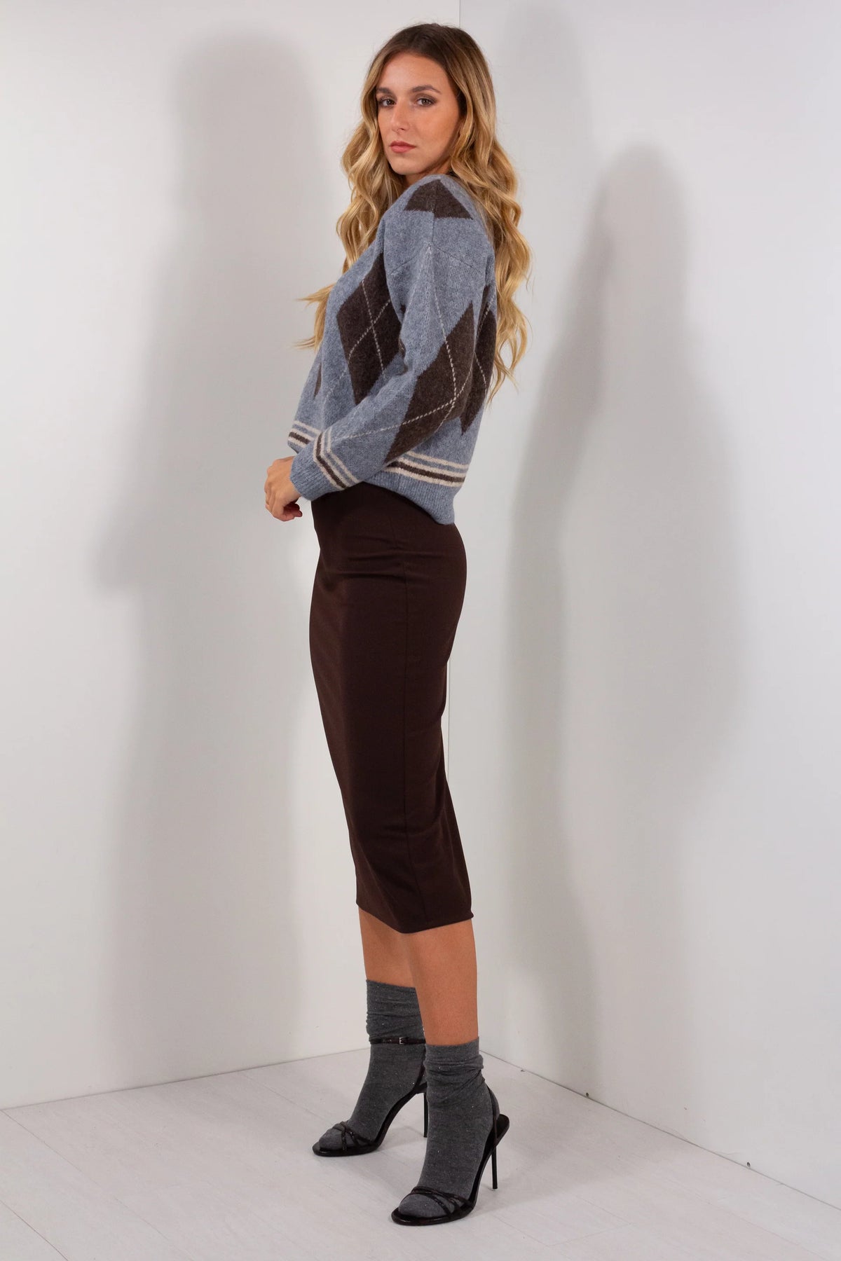 Gonna tubino spacco marrone cioccolato vista laterale tre quarti con maglione argyle grigio blu e tacchi
