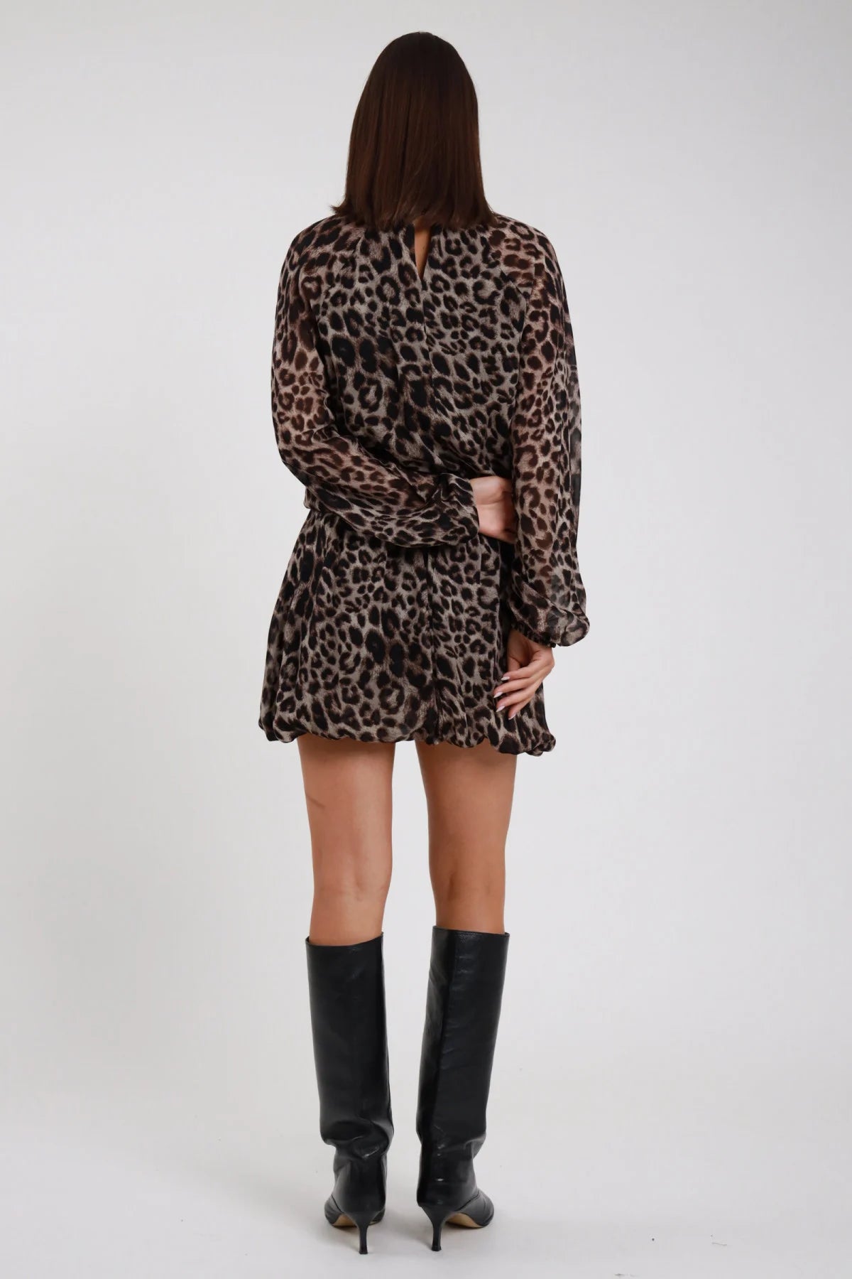 Abito Animalier leopardato maculato beige marrone nero viscosa apertura retro spacco laccetto gonna mini arricciata retro intera schiena - modella retro intera capelli castani lisci sfondo bianco stivali neri alti ginocchio
