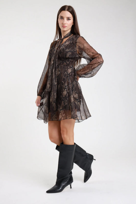 Abito corto animalier serpente pitone nero oro frontale intera fiocco lavallière rouches volant vita smock manica lunga - modella frontale intera mani fianchi sguardo frontale stivali al ginocchio neri capelli castani lisci