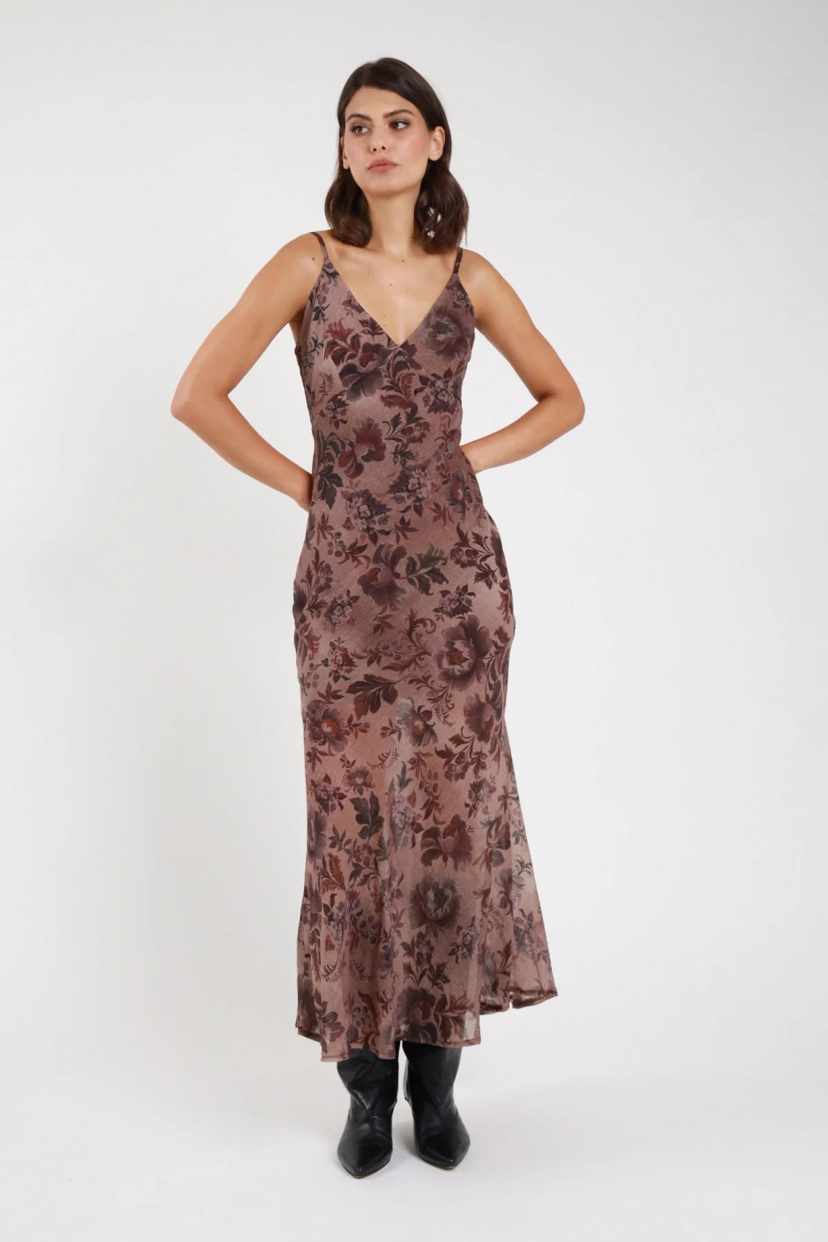 Abito lungo fantasia floreale botanica marrone bordeaux malva donna slip dress maxi scollo V spalline regolabili fit aderente svasato - vista frontale intera mani dietro la schiena con stivaletti neri