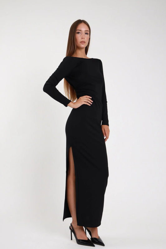 Abito lungo nero aderente scollo barca asimmetrico - modella posa laterale tre quarti con spacco laterale e slingback neri