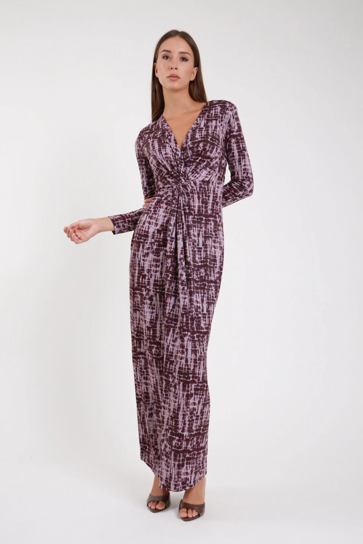 Abito lungo nodo bordeaux prugna brushstroke body-con maxi dress frontale - modella frontale intera mani ai fianchi sguardo frontale sandali marroni capelli castani lisci