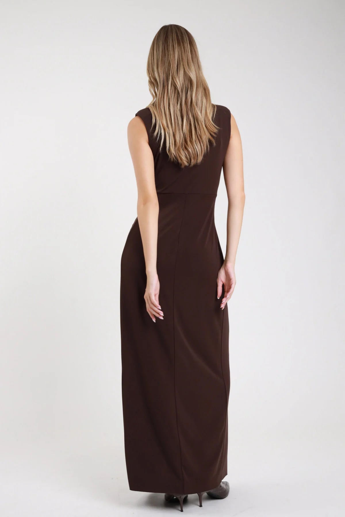 Abito maxi smanicato nodo cioccolato marrone scuro retro schiena liscia spalla imbottita - modella retro intera sguardo posteriore tacchi neri capelli biondi ondulati lunghi