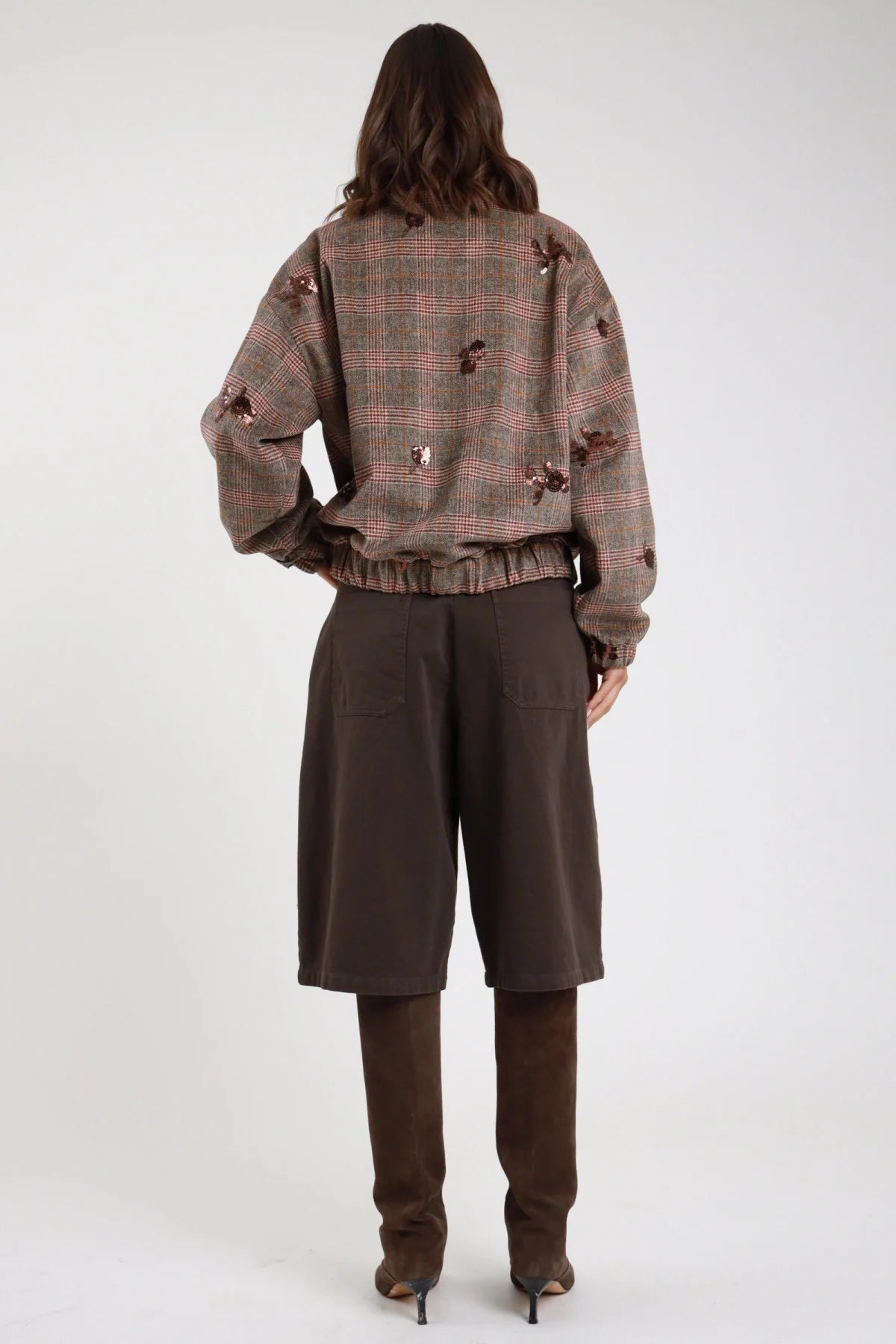 Bermuda culottes wide leg cioccolato moro scuro retro intera vita alta piega sartoriale gamba wide leg culottes below-knee orlo dritto stivali marroni alti - modella retro intera capelli castani mossi con giacca bomber check tartan paillettes cipria stivali marroni alti sfondo bianco