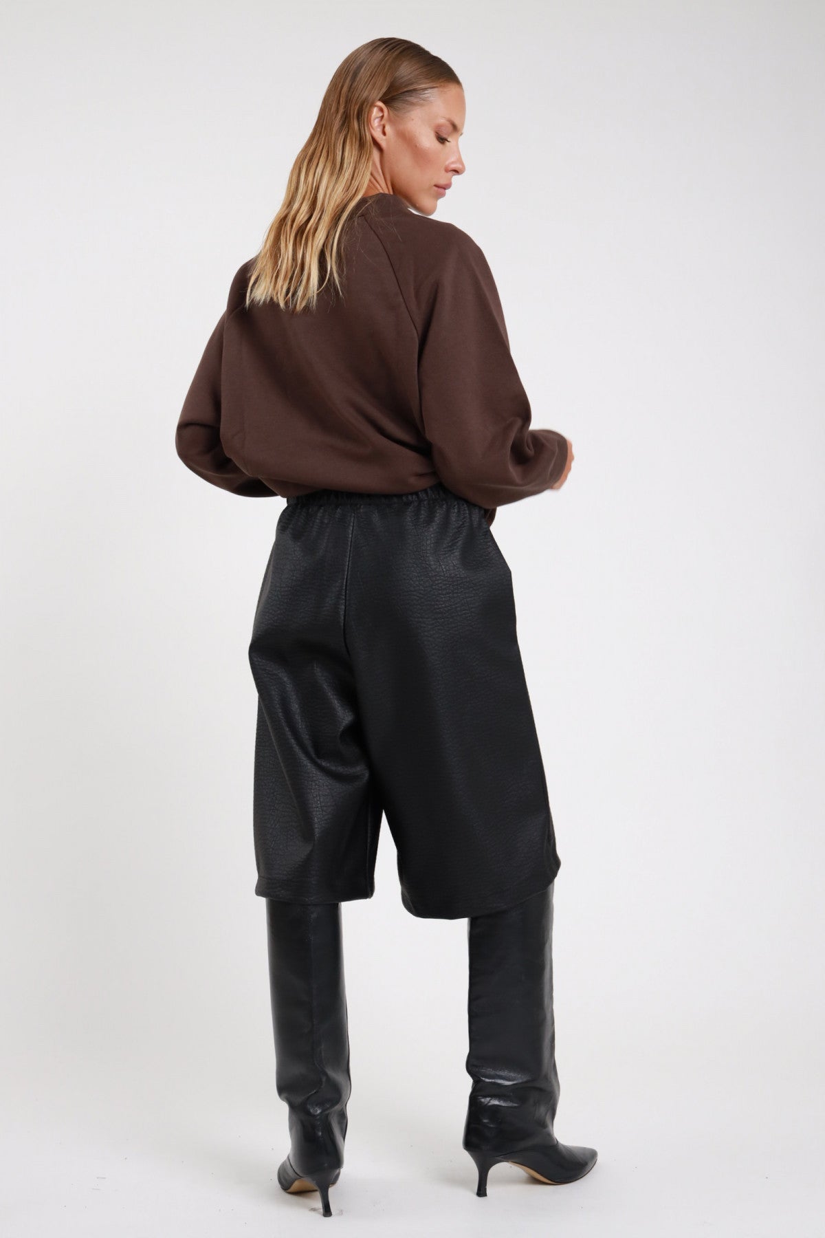 Bermuda ecopelle croco nero retro elastico vita culotte wide-leg orlo dritto - modella retro intera sguardo basso felpa Brooklyn cioccolato stivali neri al ginocchio tacco capelli biondi mossi
