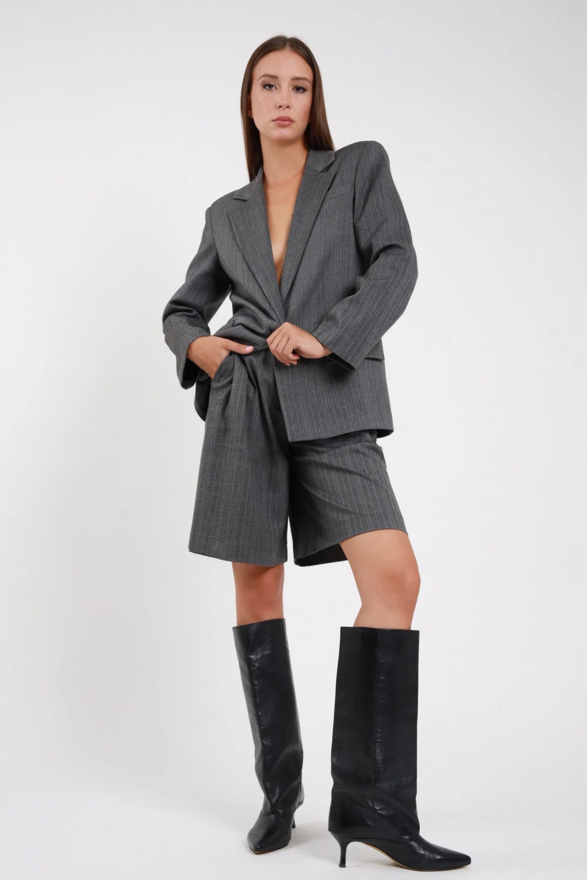 Bermuda Spinato herringbone grigio antracite lurex vita alta pince wide ginocchio frontale intera coordinato blazer grigio - modella frontale intera sguardo camera capelli castani lisci sfondo bianco blazer grigio spinato stivali neri alti tacco kitten