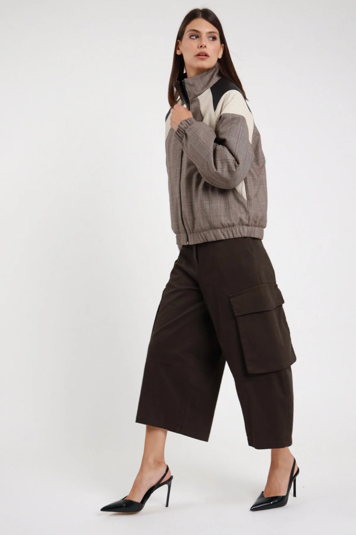 Bermuda Tasconi cioccolato marrone scuro 97% cotone tasconi cargo gamba wide leg culotte 3/4 laterale posa in cammino sguardo 3/4 - modella intera 3/4 laterale posa in cammino sguardo 3/4 capelli castani scuri lisci sfondo bianco bomber check color block grigio abbinato slingback tacco neri