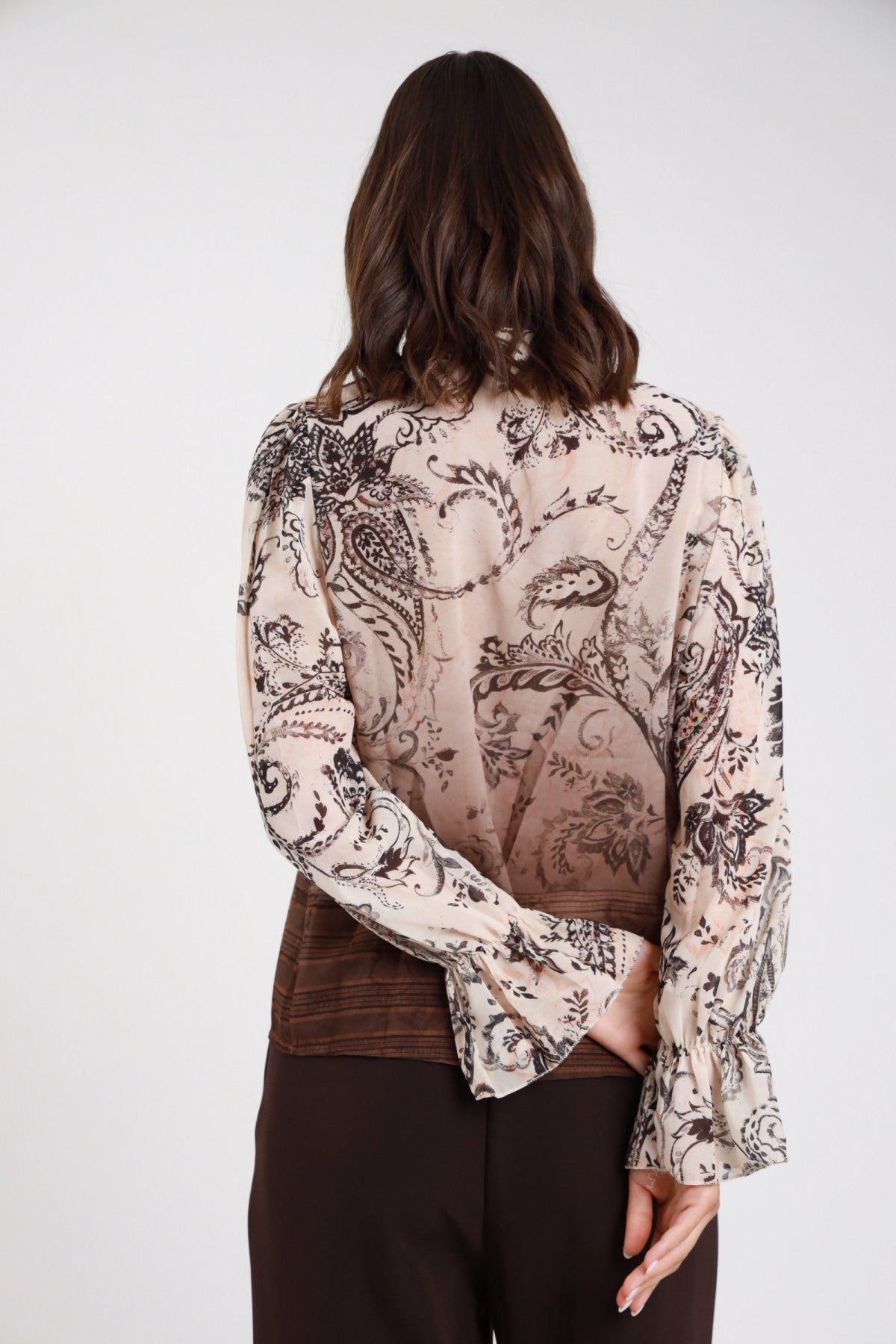 Blusa fantasia paisley baroque chiffon panna ecru cioccolato moro degrade retro intera colletto fiocco manica balloon bishop ampia polsino balze ruches svasato laccetto fiocco corpo regular crop orlo degrade cioccolato bordura tessuta fondo - modella retro intera sguardo basso pantaloni marroni capelli castani mossi sfondo bianco