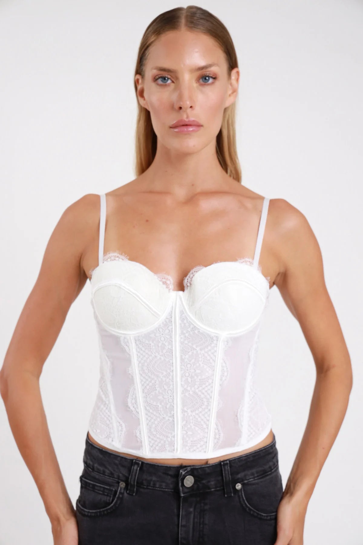 Top bustino corset bianco coppa push-up balconcino bordino pizzo décolleté stecche boning frontale intera - modella frontale intera mani fianchi sguardo frontale jeans denim nero capelli biondi lisci
