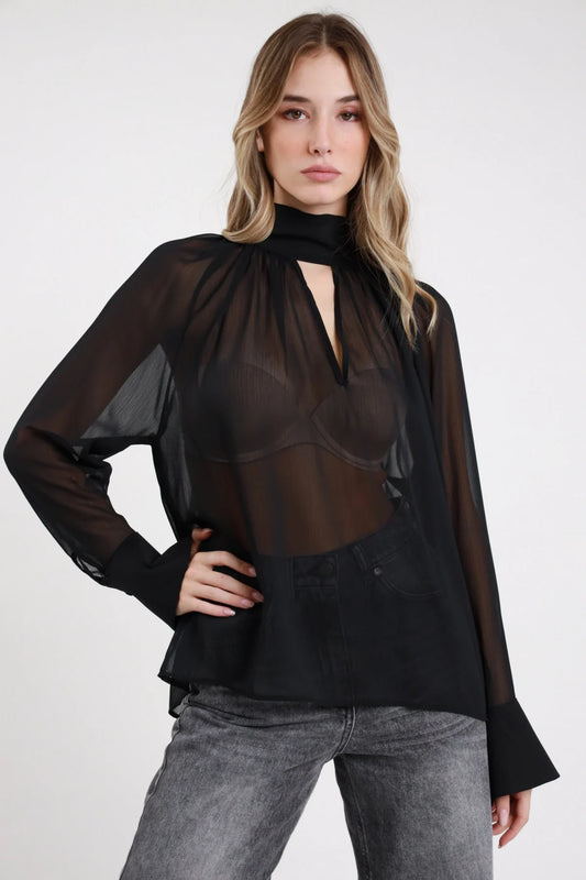 Camicia fiocco Susy Mix nera semitrasparente con scollatura a goccia e maniche lunghe, indossata con jeans