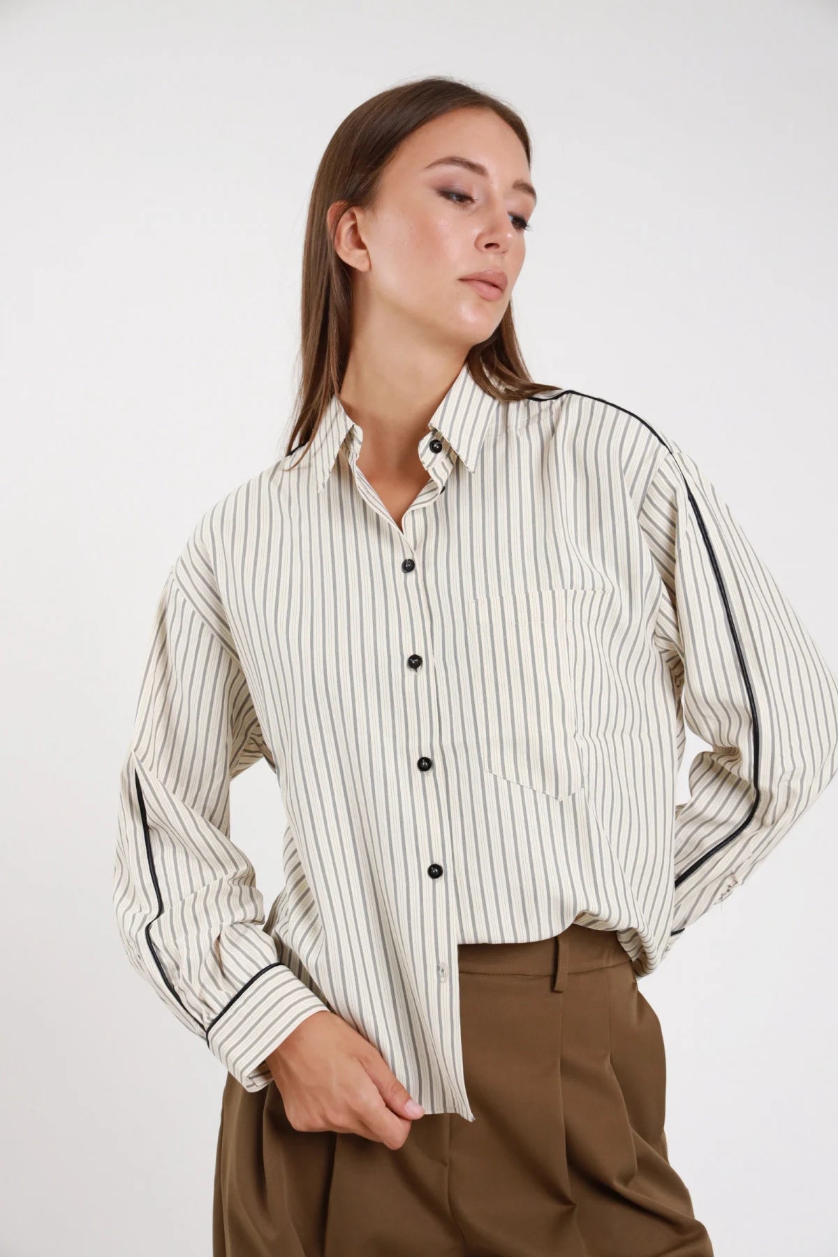 Camicia piping righe verticali panna kaki boxy oversize - modella busto frontale mani sui fianchi sguardo basso con pantaloni kaki capelli sciolti