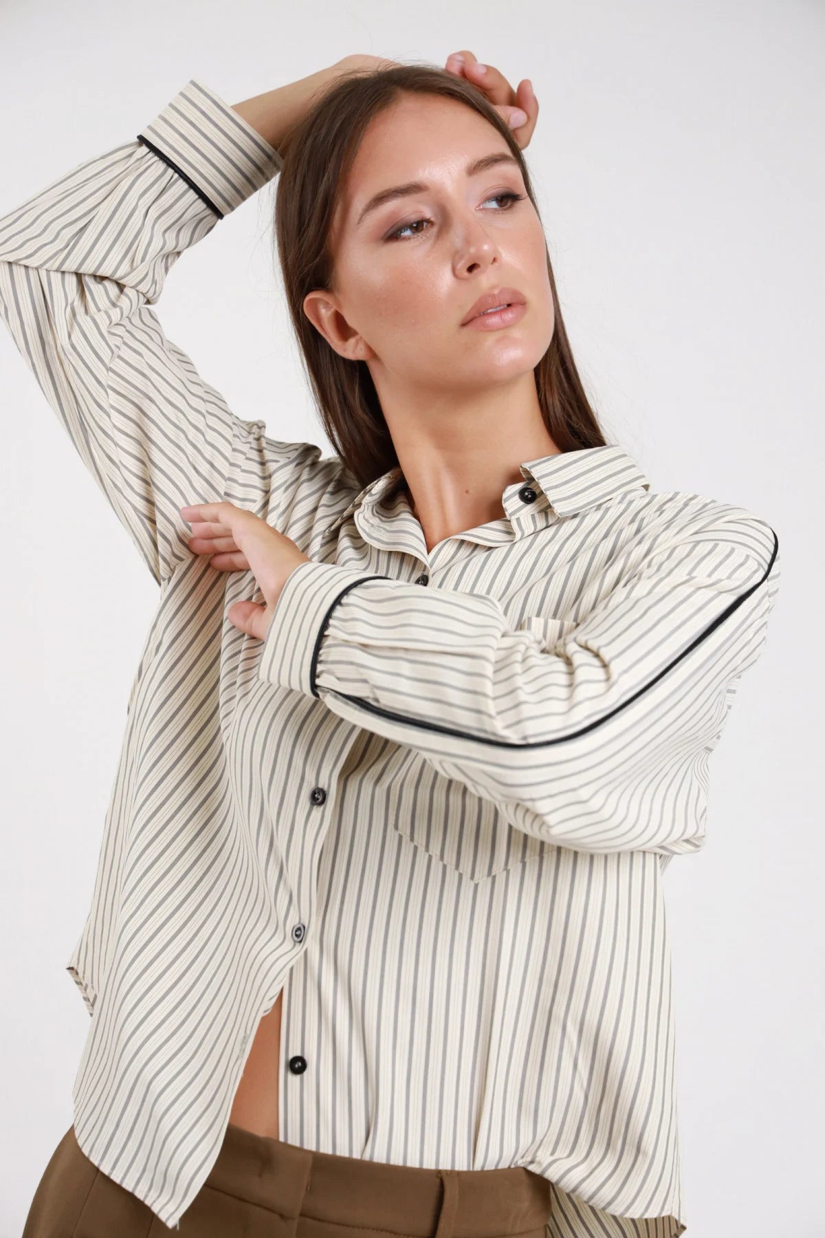 Camicia righe piping nero polsini dettaglio - modella busto braccia alzate mano in testa piping polsini visibile sguardo sognante capelli sciolti