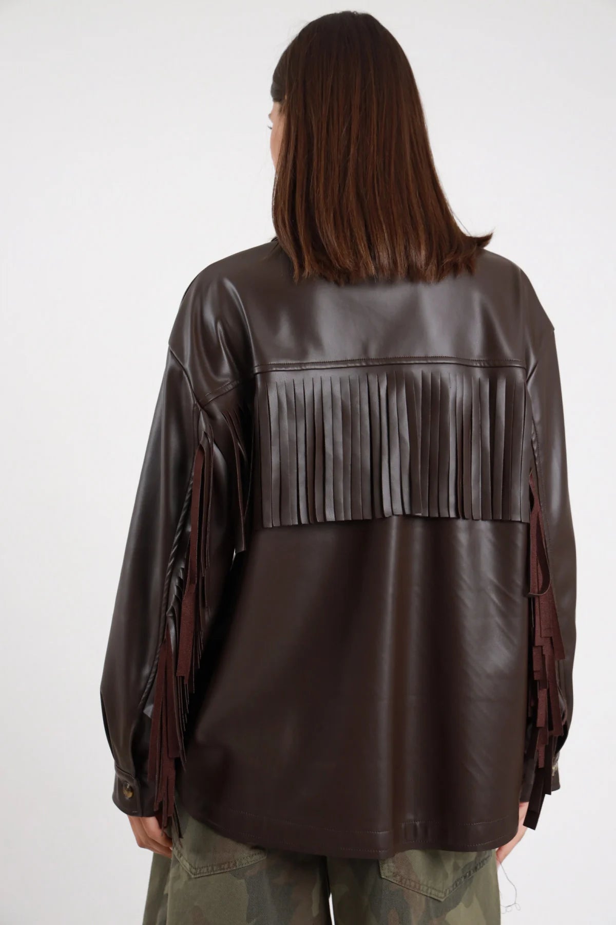 Camicia Ecopelle Frange marrone cioccolato 50% PU maxi frangia orizzontale retro sotto spalle frange maniche posteriore silhouette oversize boxy lunga - modella intera posteriore posa statica capelli castani scuri sfondo bianco bermuda mimetico woodland