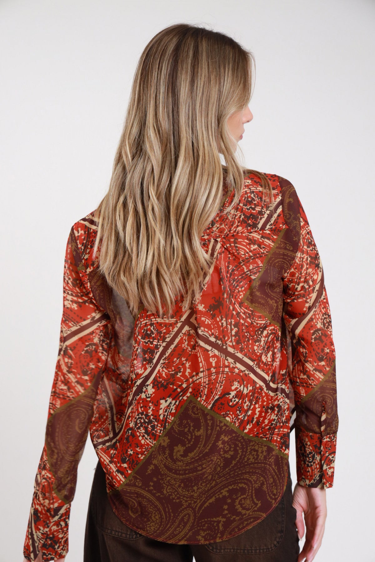 Camicia fantasia paisley cachemire rosso borgogna frontale tre quarti mani fianchi corpo oversize colletto classico - modella frontale tre quarti mani fianchi sguardo frontale pantaloni marrone scuro capelli biondi ondulati