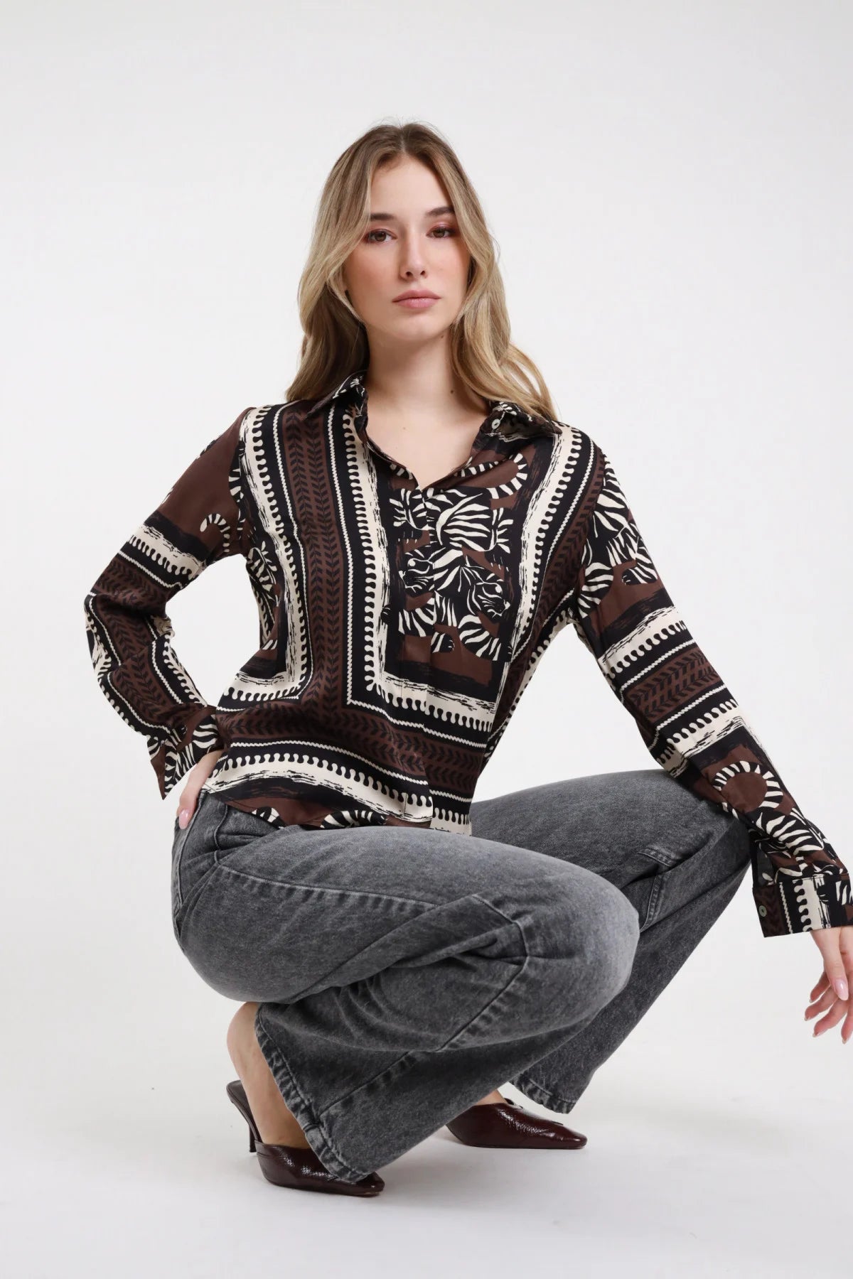 Camicia fantasia Susy Mix marrone con motivi botanici e bordure panna e nere, indossata con jeans grigi